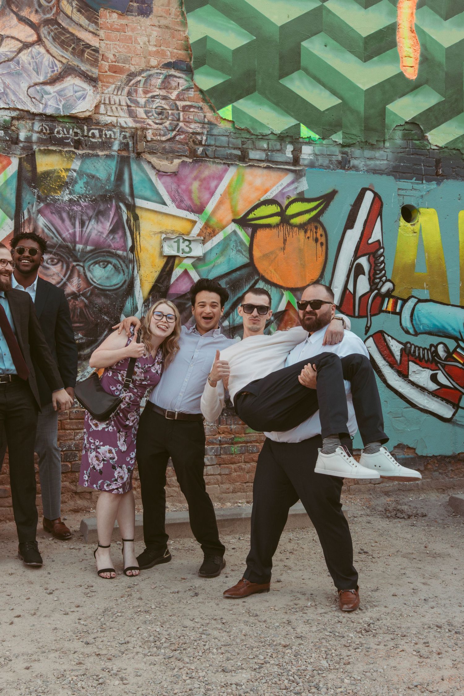 Fun wedding party posing in front of colorful graffiti wall art.