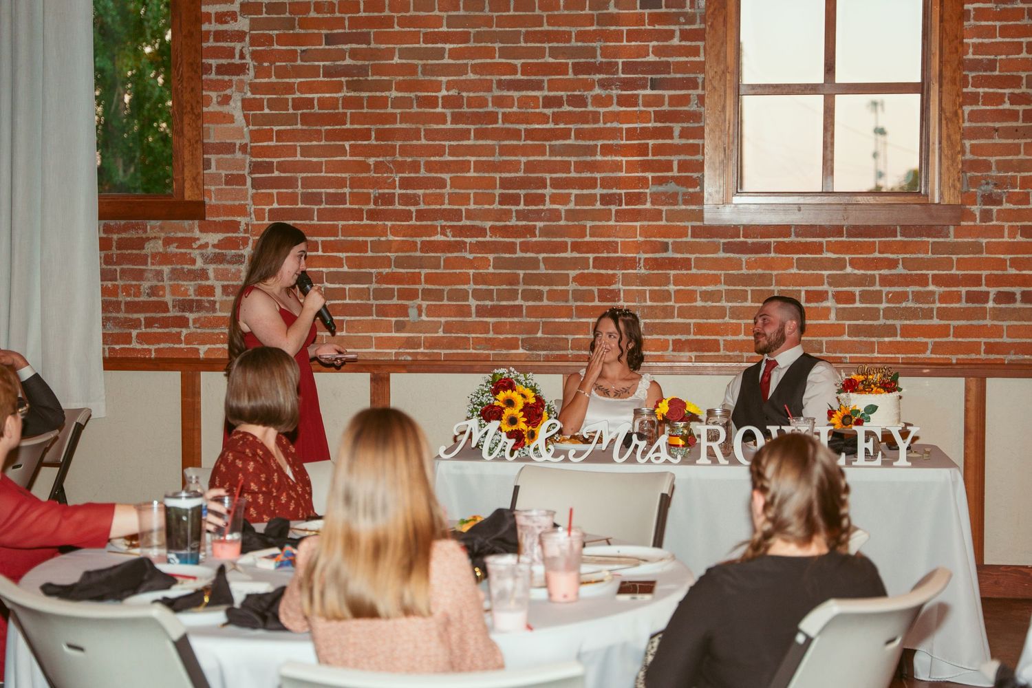 Wedding reception hall with brick walls and sunlight streaming through windows.