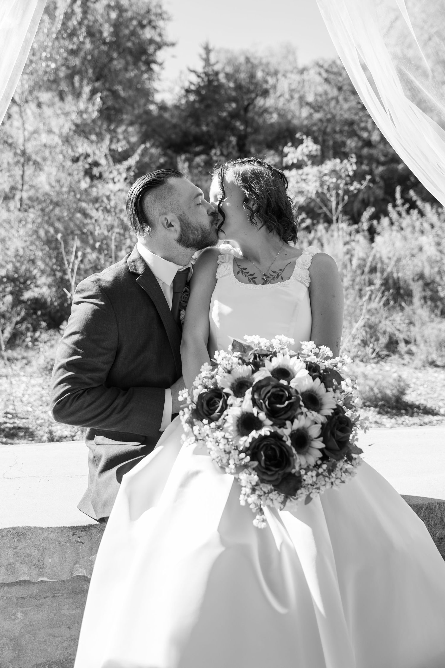Black and white wedding portraits showing romantic moments under outdoor pavilion.