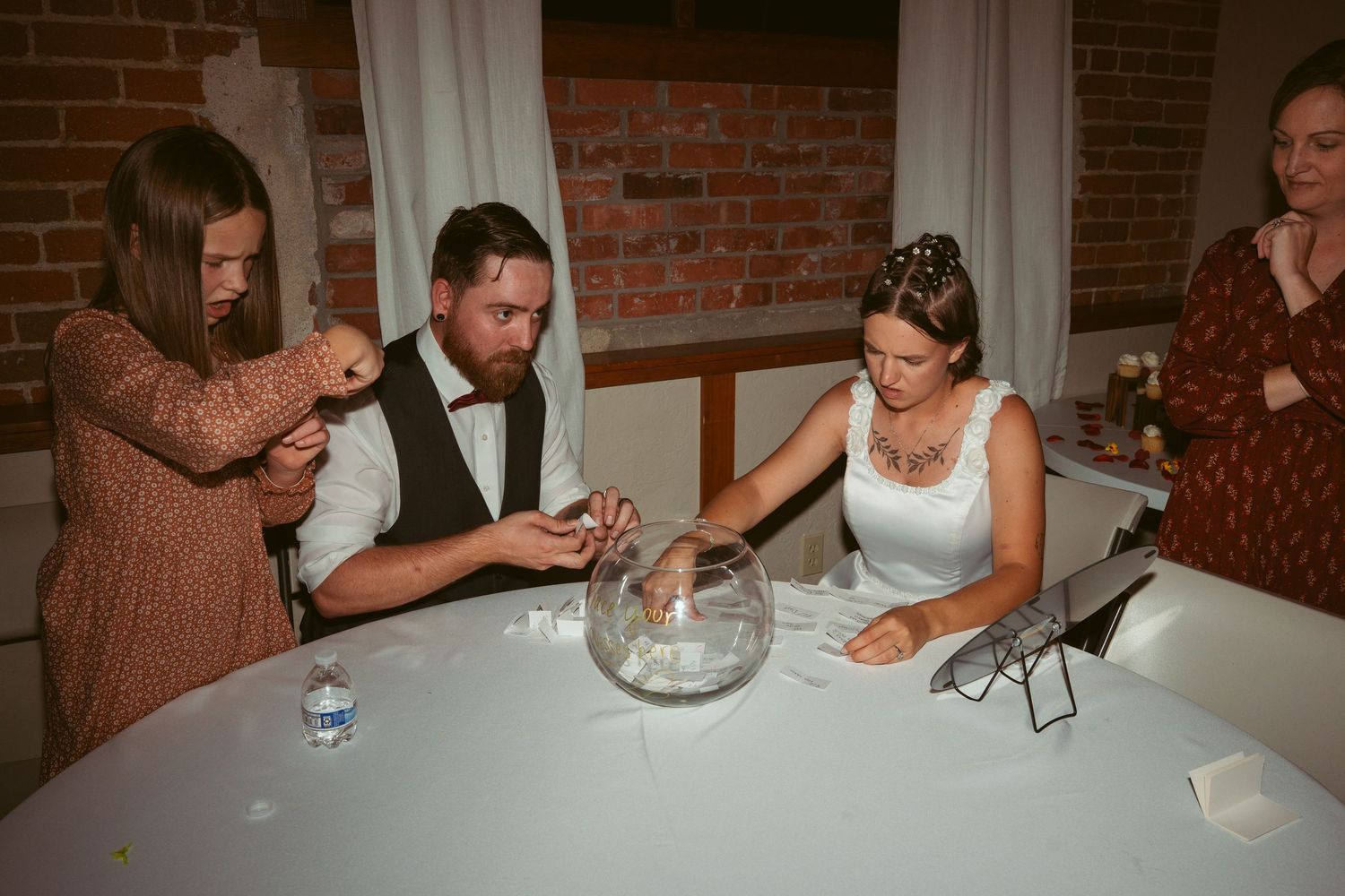 Event guests seated at tables with white linens against exposed brick walls.