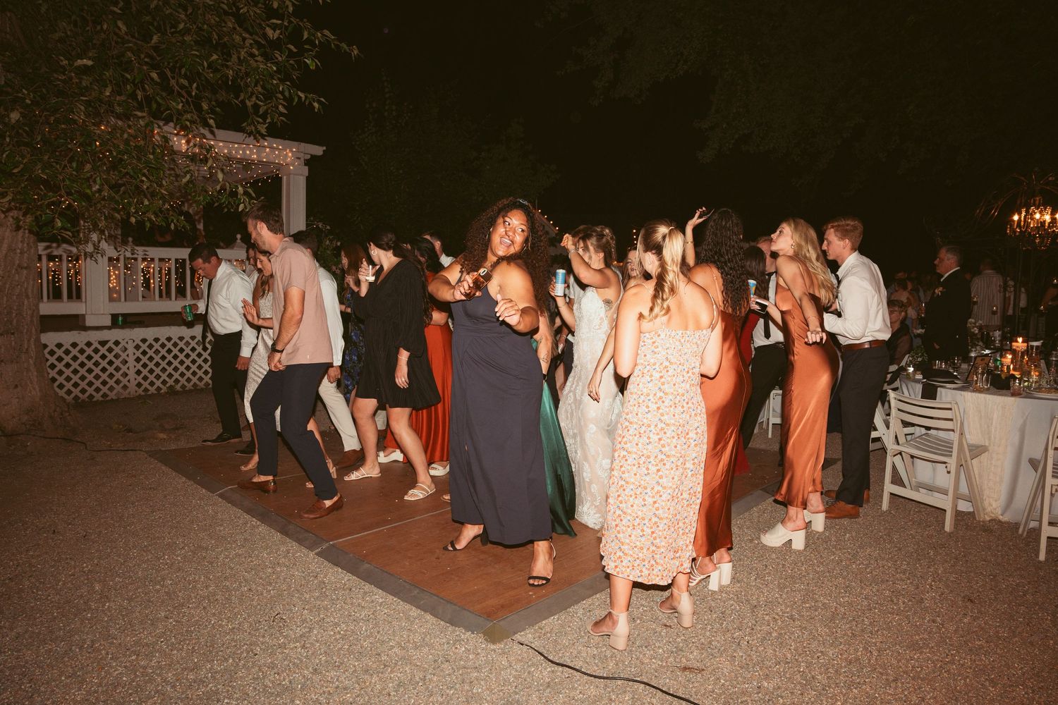 Wedding guests mingling and dancing at an outdoor nighttime celebration.