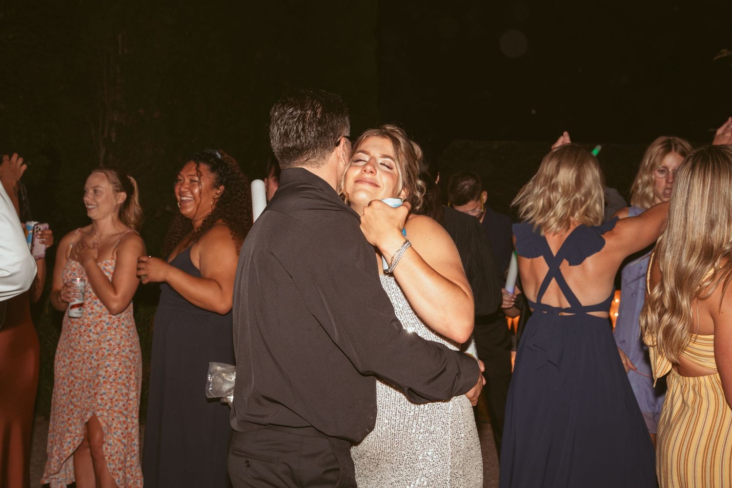 Couples and guests dancing together during a wedding reception celebration.