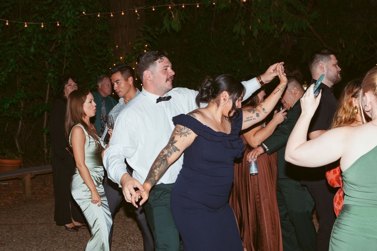 Wedding celebration dance floor filled with guests enjoying the evening under string lights.