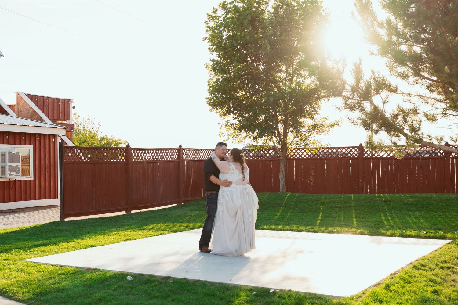 Wedding party posing in front of a red barn during golden hour.