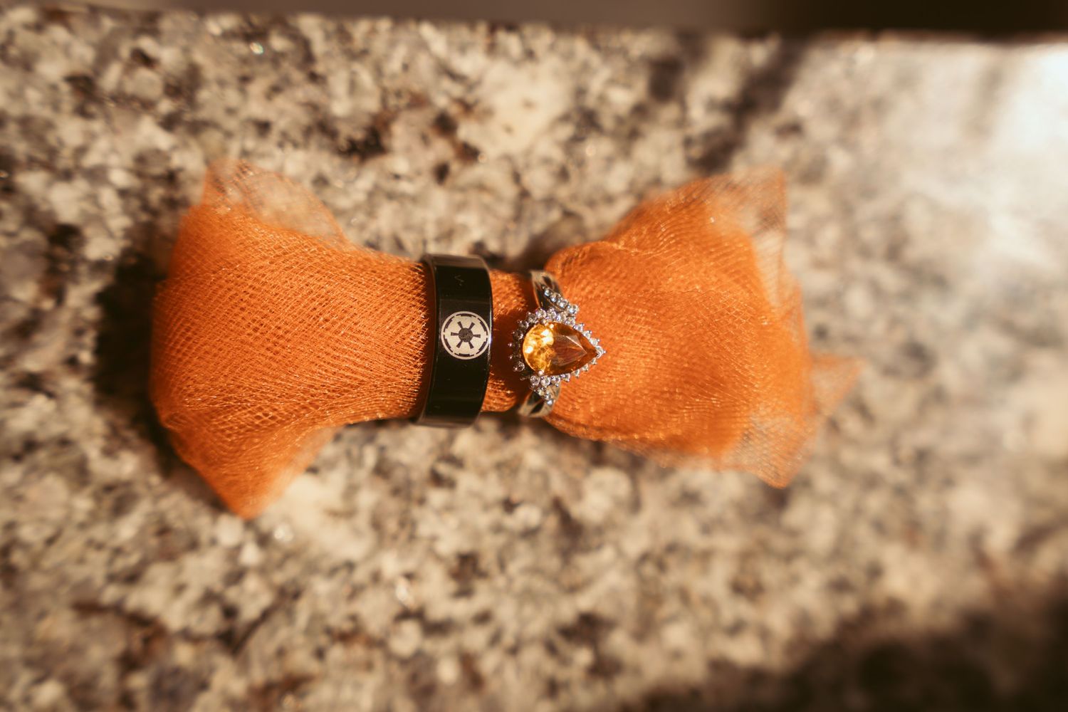 Close-up of orange bow tie and wedding ring details.