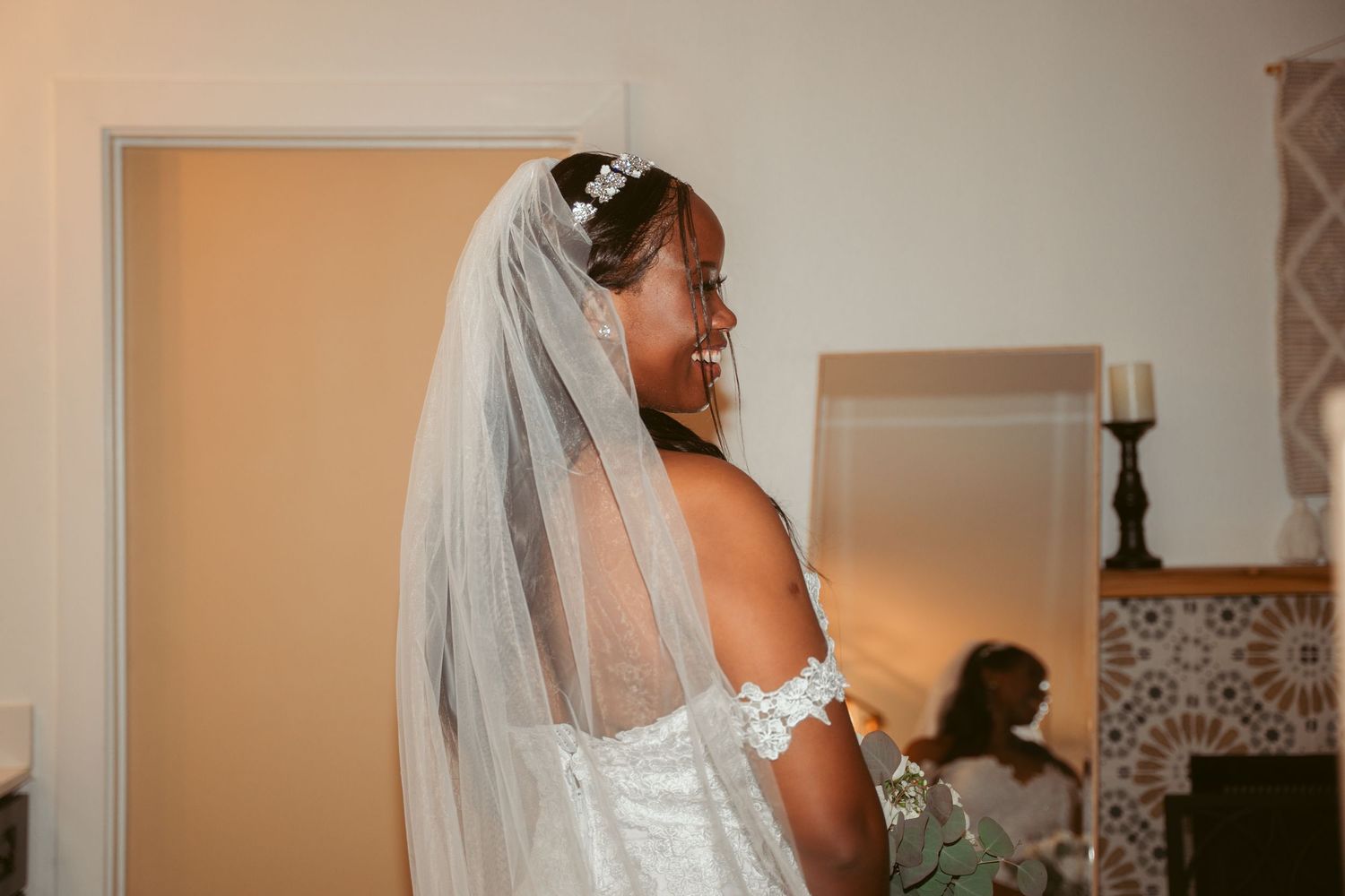 A bride in a white lace dress and flowing veil photographed from behind.
