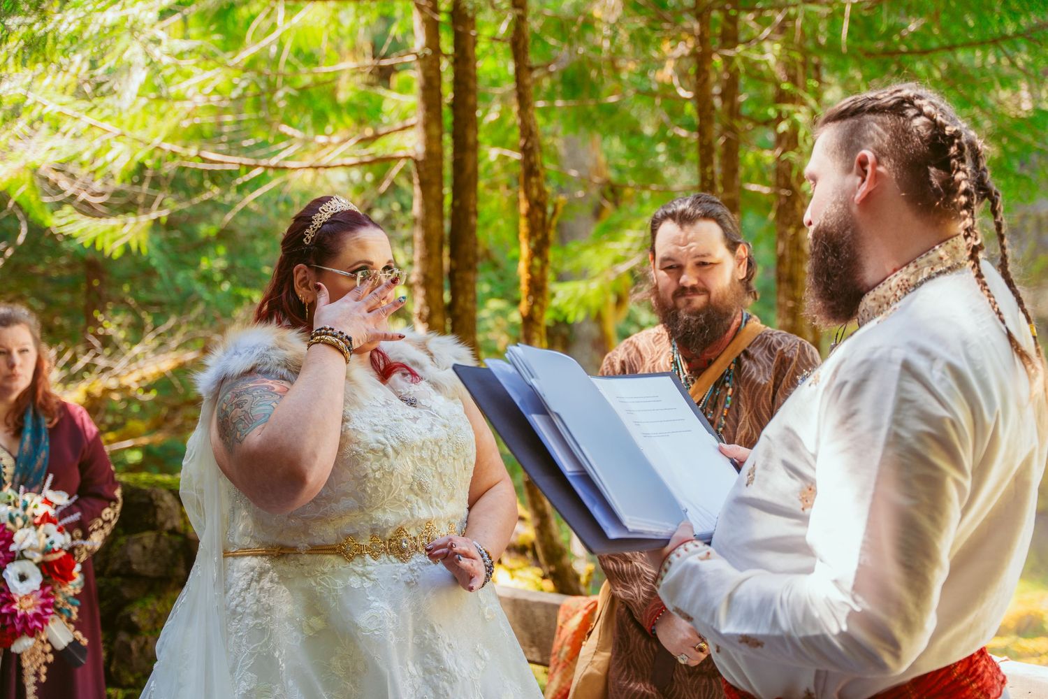 Wedding attendees gather in a forest setting during an outdoor ceremony.