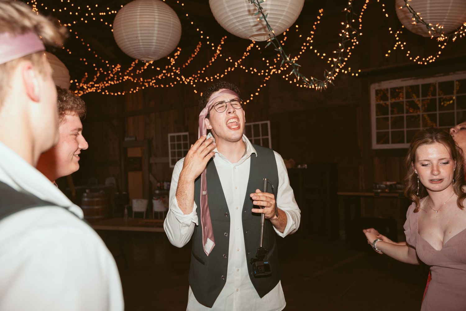 Energetic dancing at a wedding reception with decorative lighting and paper lanterns.