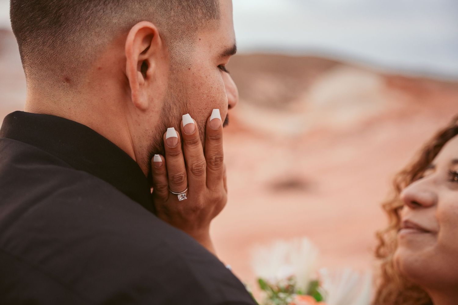 Close-up shots of wedding couple sharing intimate moments in desert setting.
