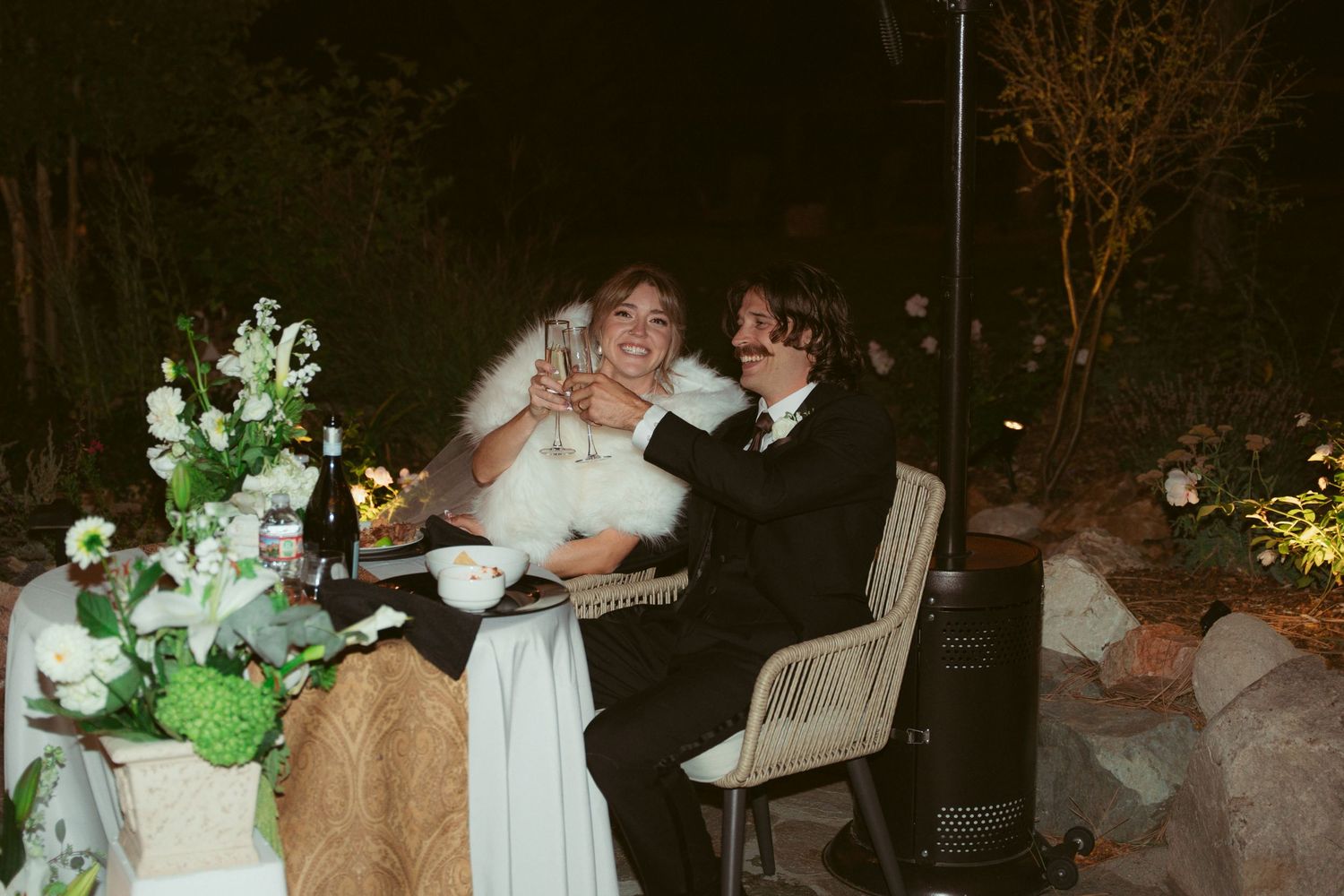 Couple shares intimate moment at their wedding reception with decorative white flowers in the foreground.