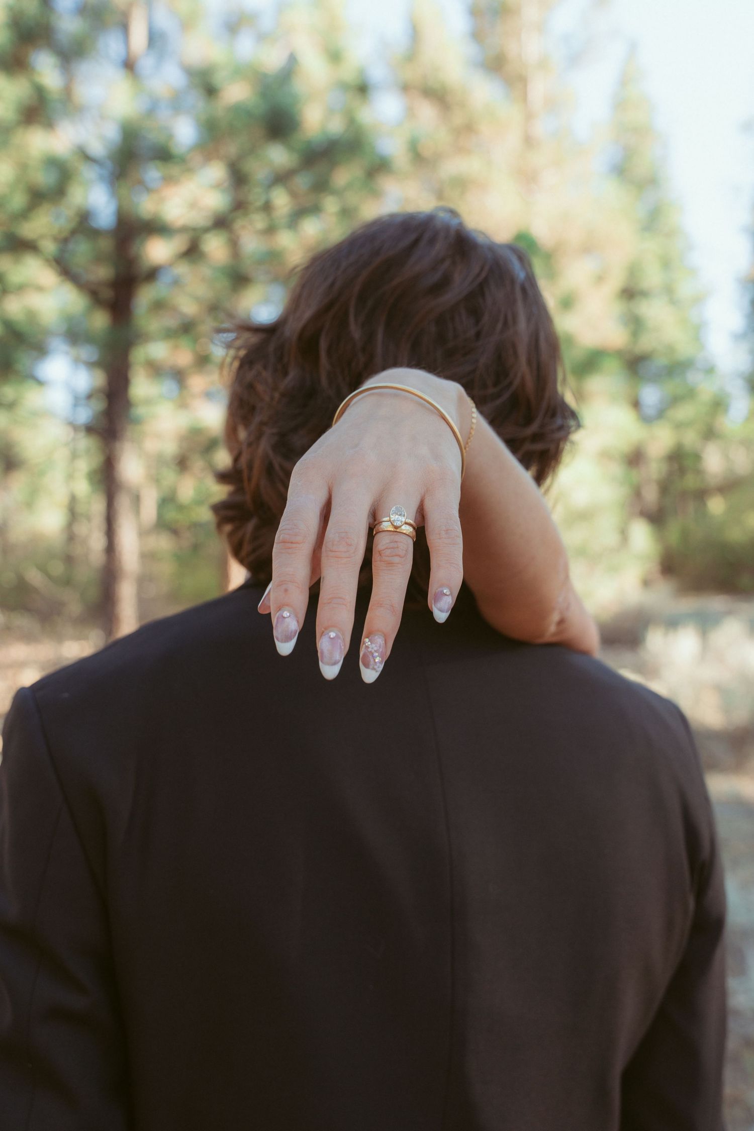 Close-up of a wedding ring displayed as hands rest on formal attire.