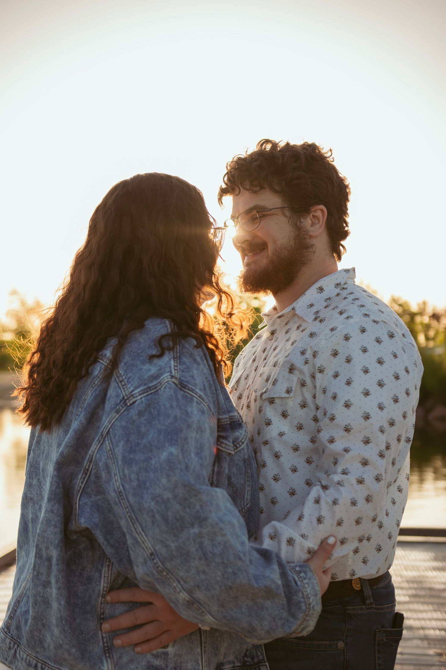 Romantic couple embracing in denim and polka dots during sunset by the water.