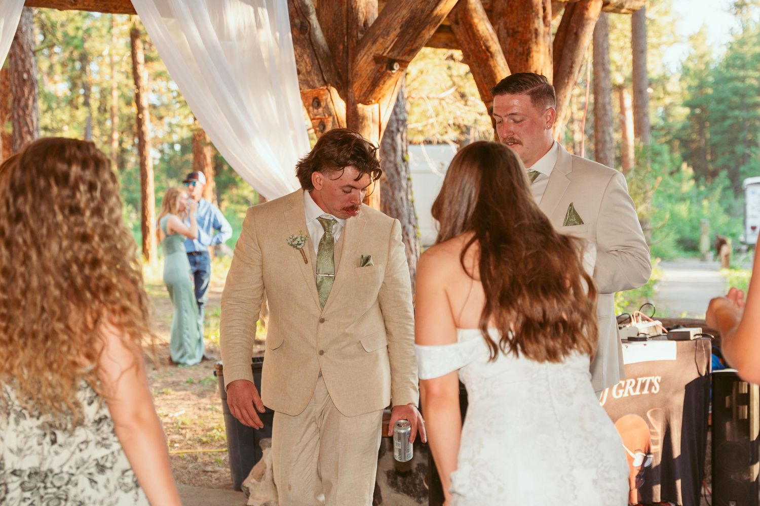 Wedding party members dancing and celebrating at a rustic outdoor reception venue.