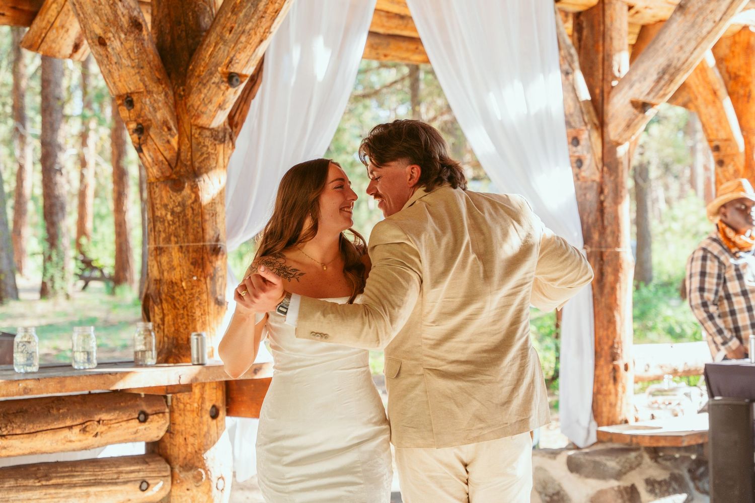 Wedding celebration inside a rustic timber lodge decorated with white drapes and natural light.