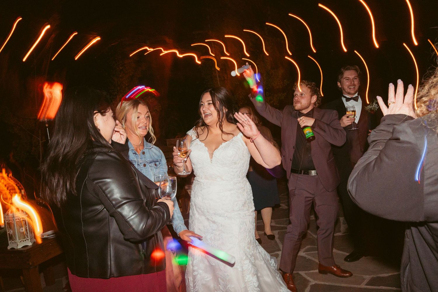 Lively dance floor scene at a wedding with string lights overhead and guests in formal attire.