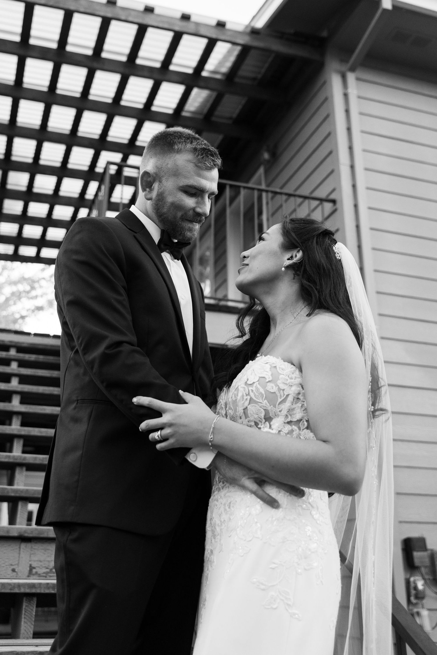 Intimate wedding moment captured under a white pergola during an outdoor ceremony.
