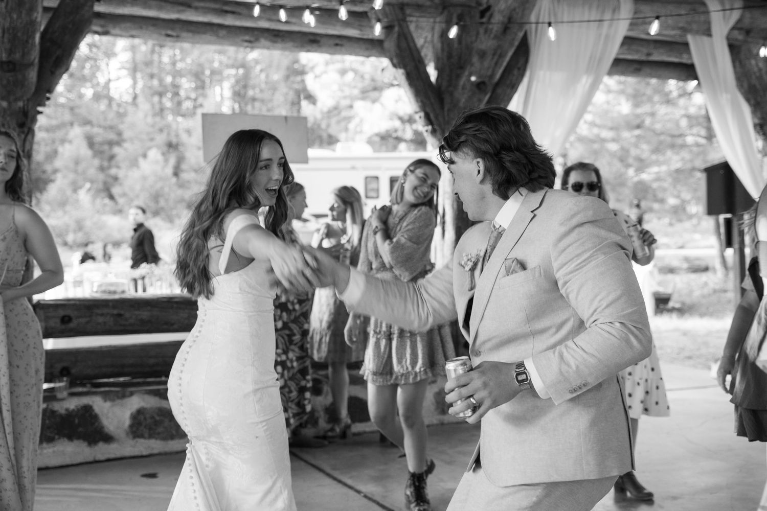 Black and white photo of couples dancing at an outdoor wedding reception.