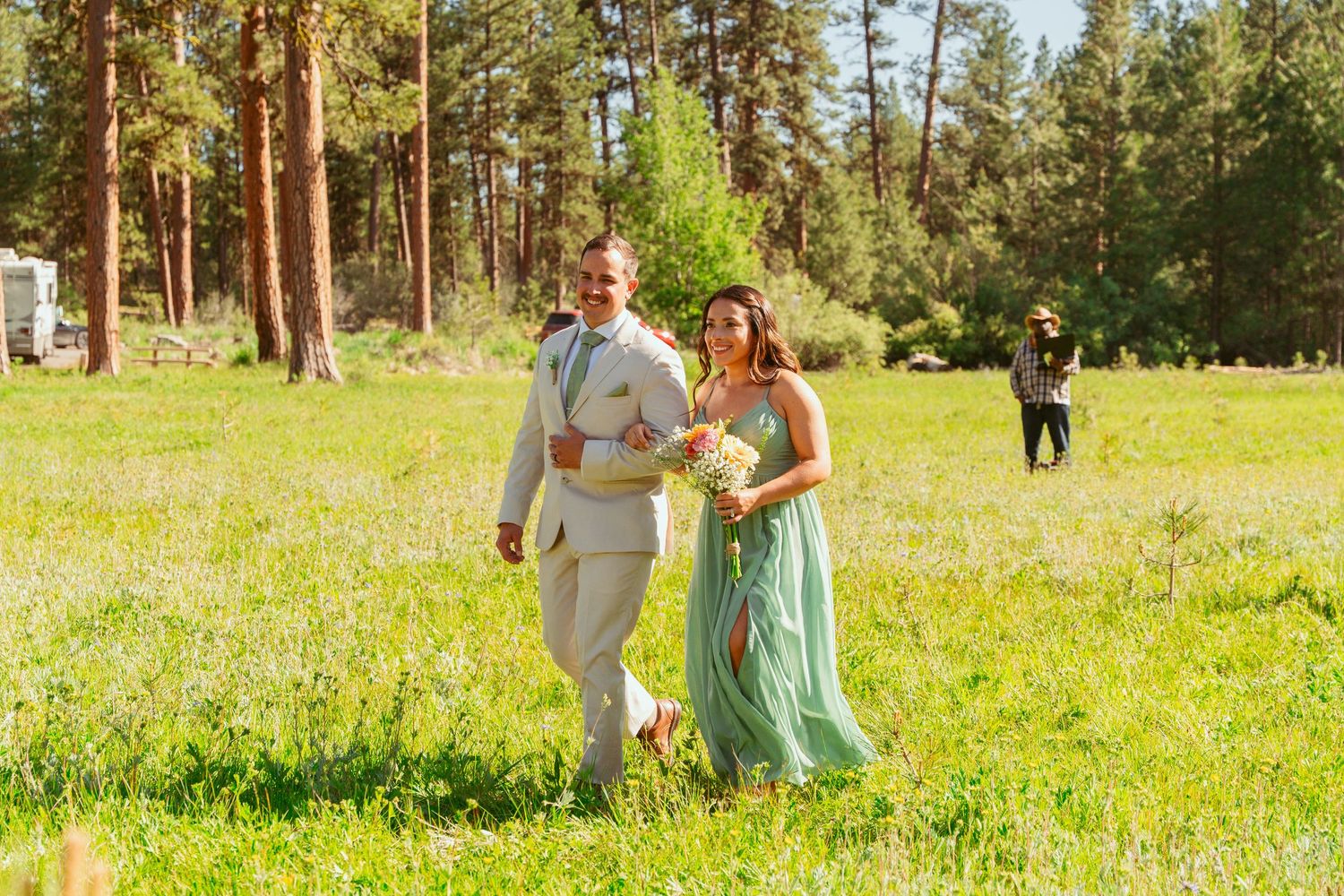 Outdoor wedding ceremony in a mountain meadow with towering pines creating a natural backdrop.