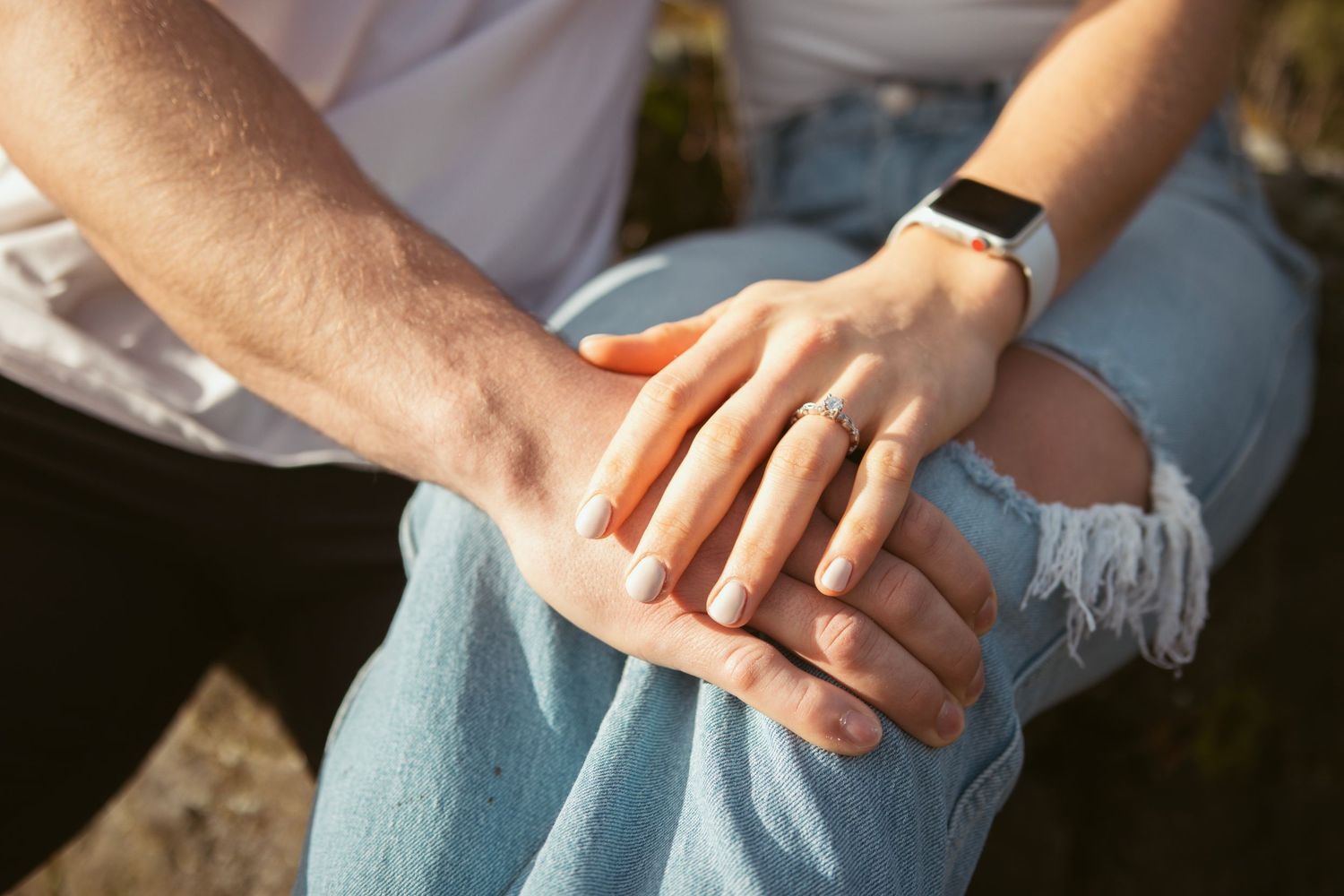 Close-up details of hands and casual clothing in natural outdoor lighting.