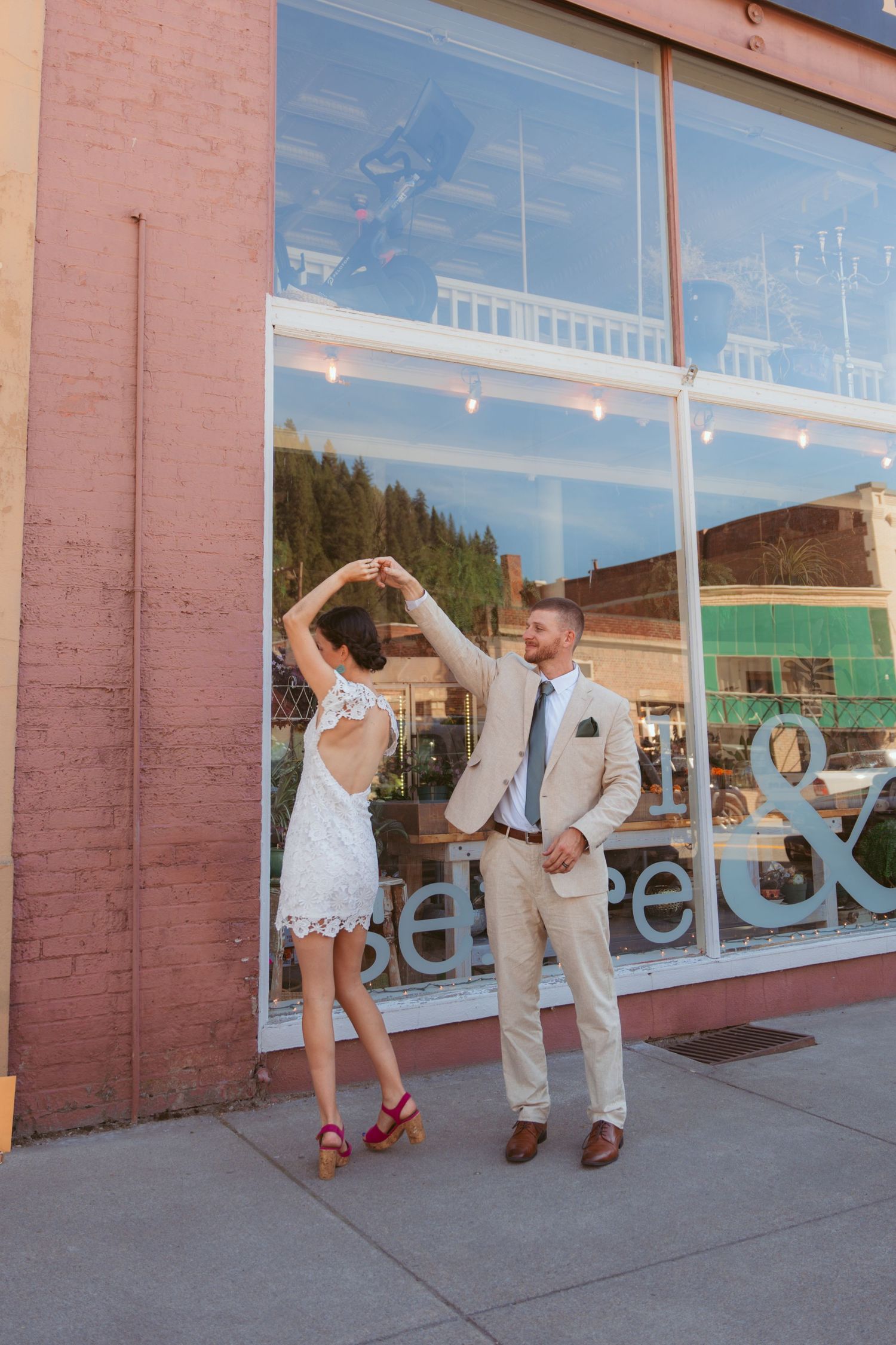 Fun wedding photo session against brick building with large windows.