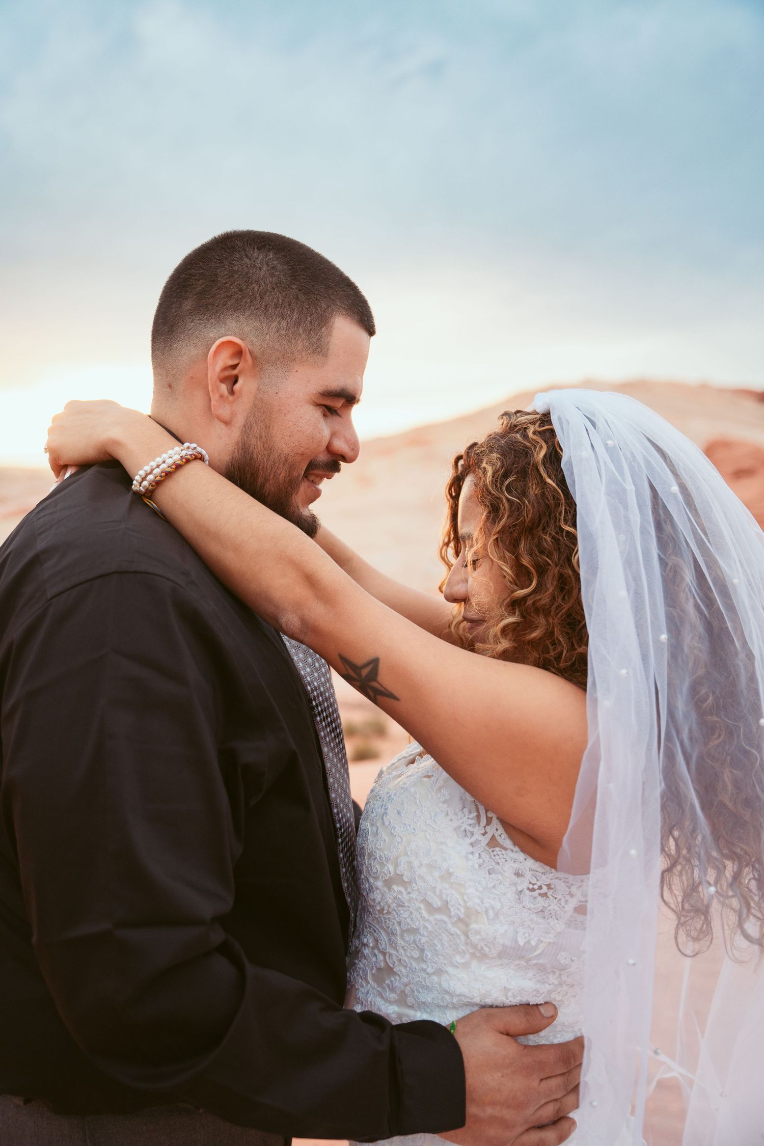 A tender moment between newlyweds against a sunset desert backdrop.