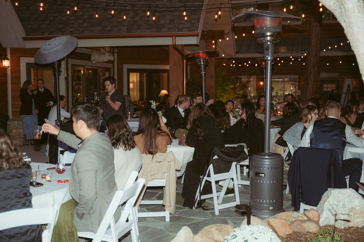 Wedding guests seated at decorated tables during an evening outdoor reception.