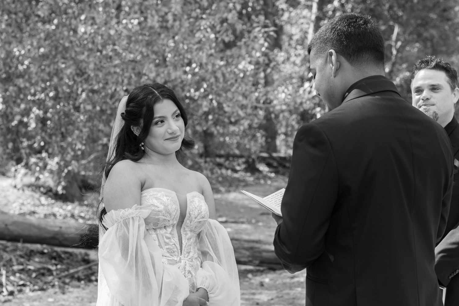 Black and white photo of intimate wedding ceremony moment in a natural outdoor setting.