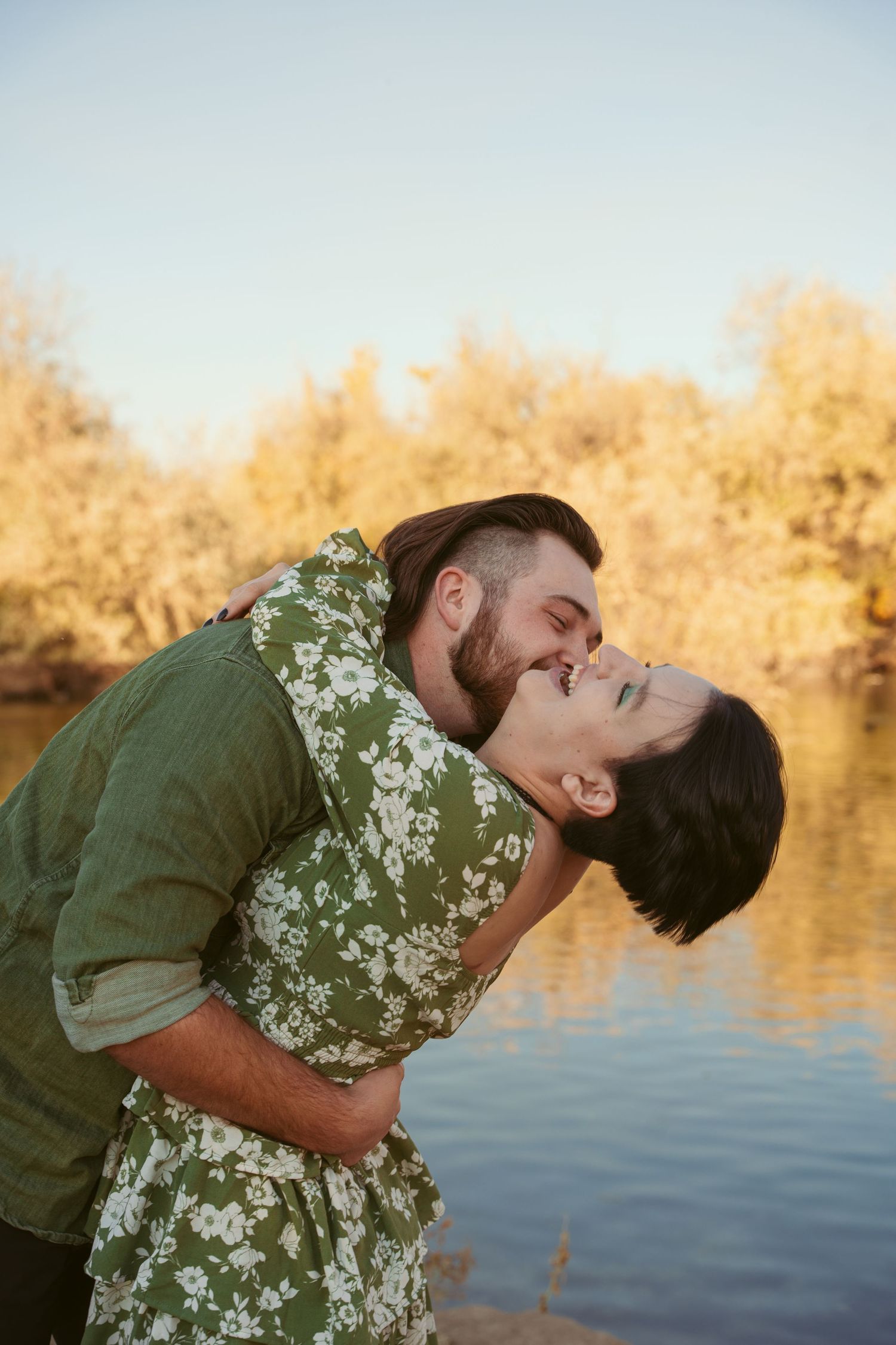 A romantic dip pose against a serene lake backdrop at sunset.