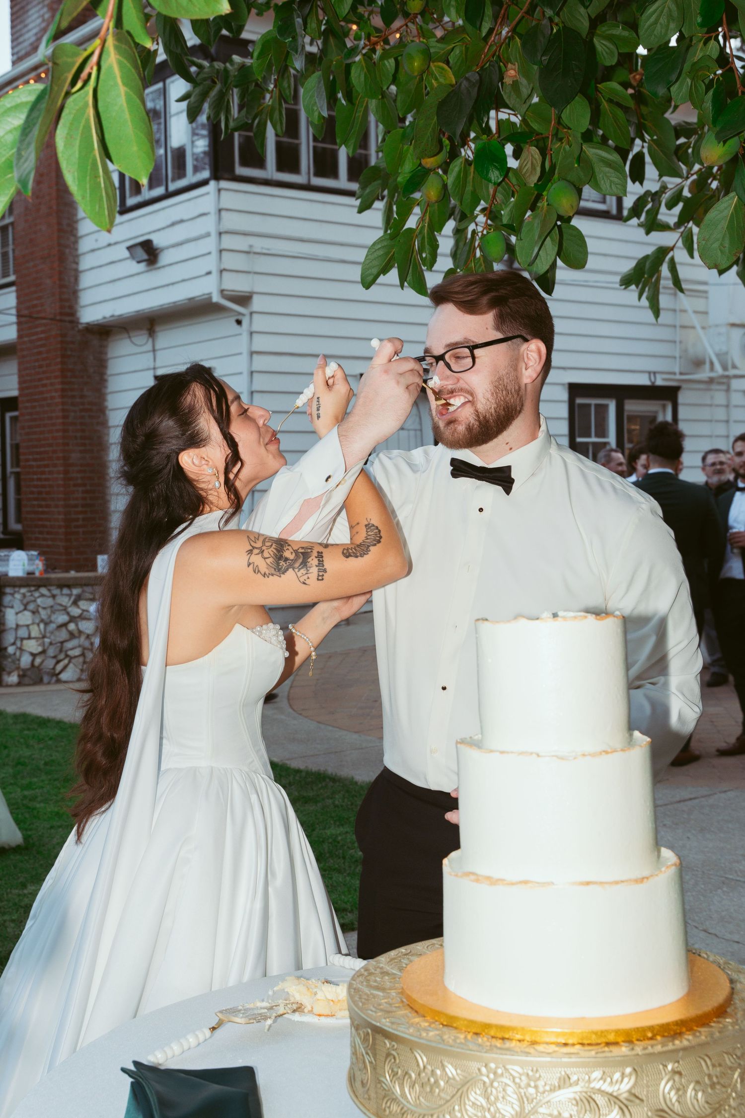 Playful moment of couple feeding each other wedding cake during reception.