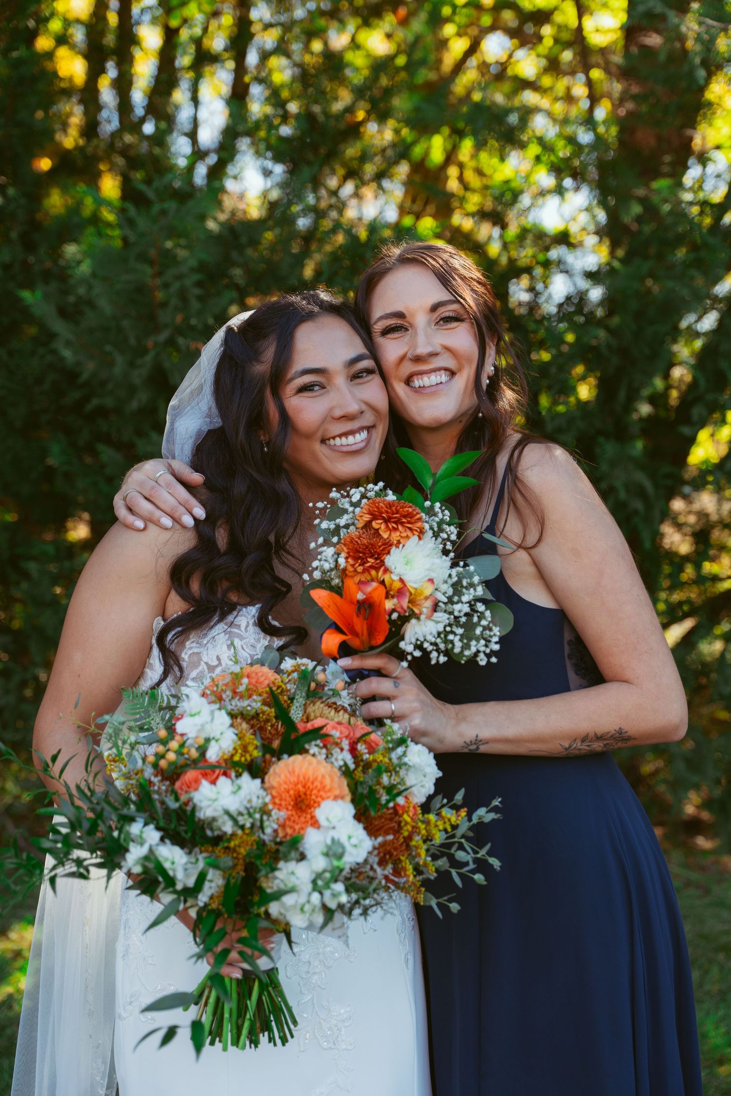 Candid embrace captured during outdoor wedding photography with vibrant orange and white bouquet.