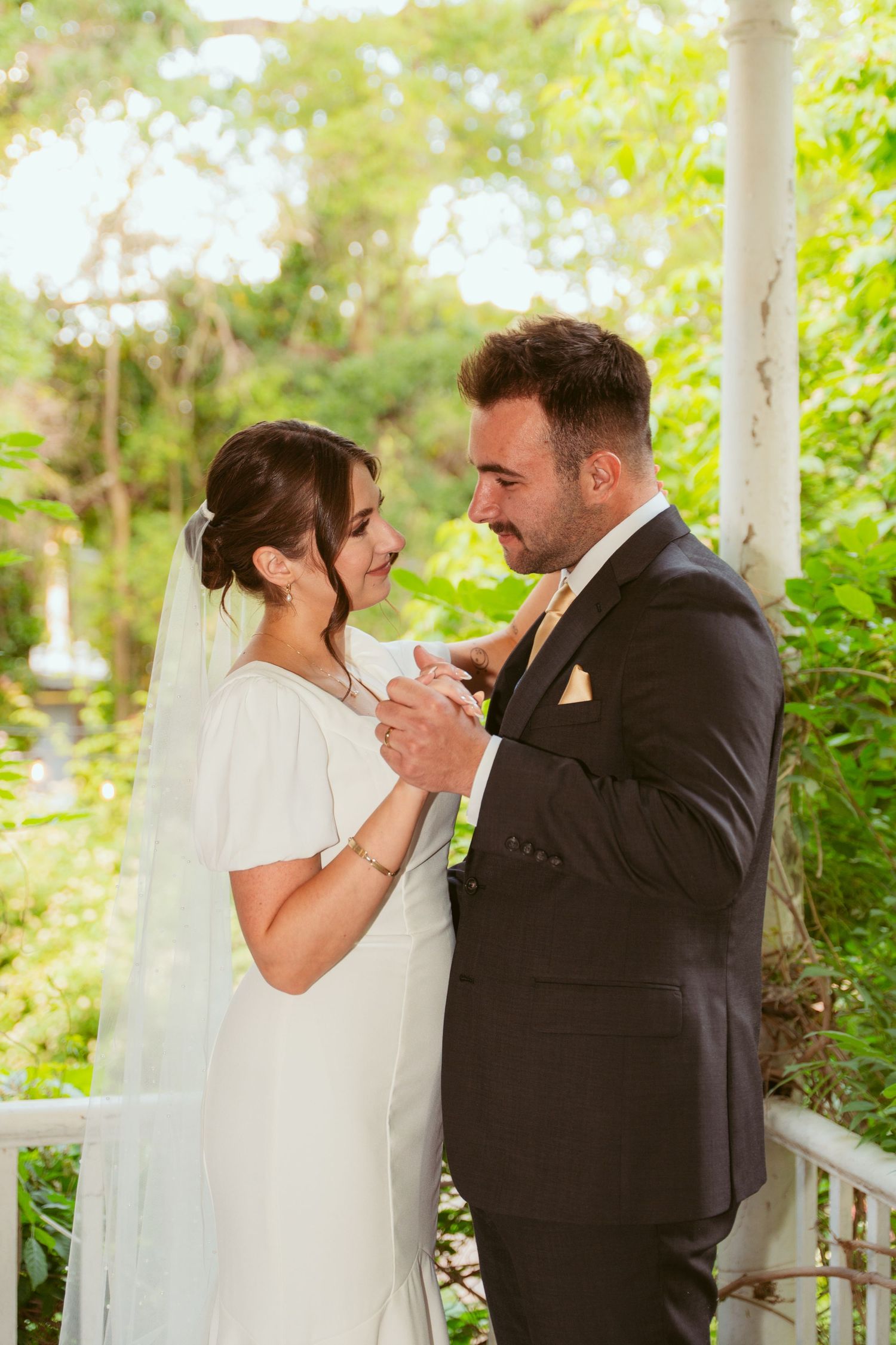 Intimate wedding portraits on a white columned porch surrounded by lush greenery.