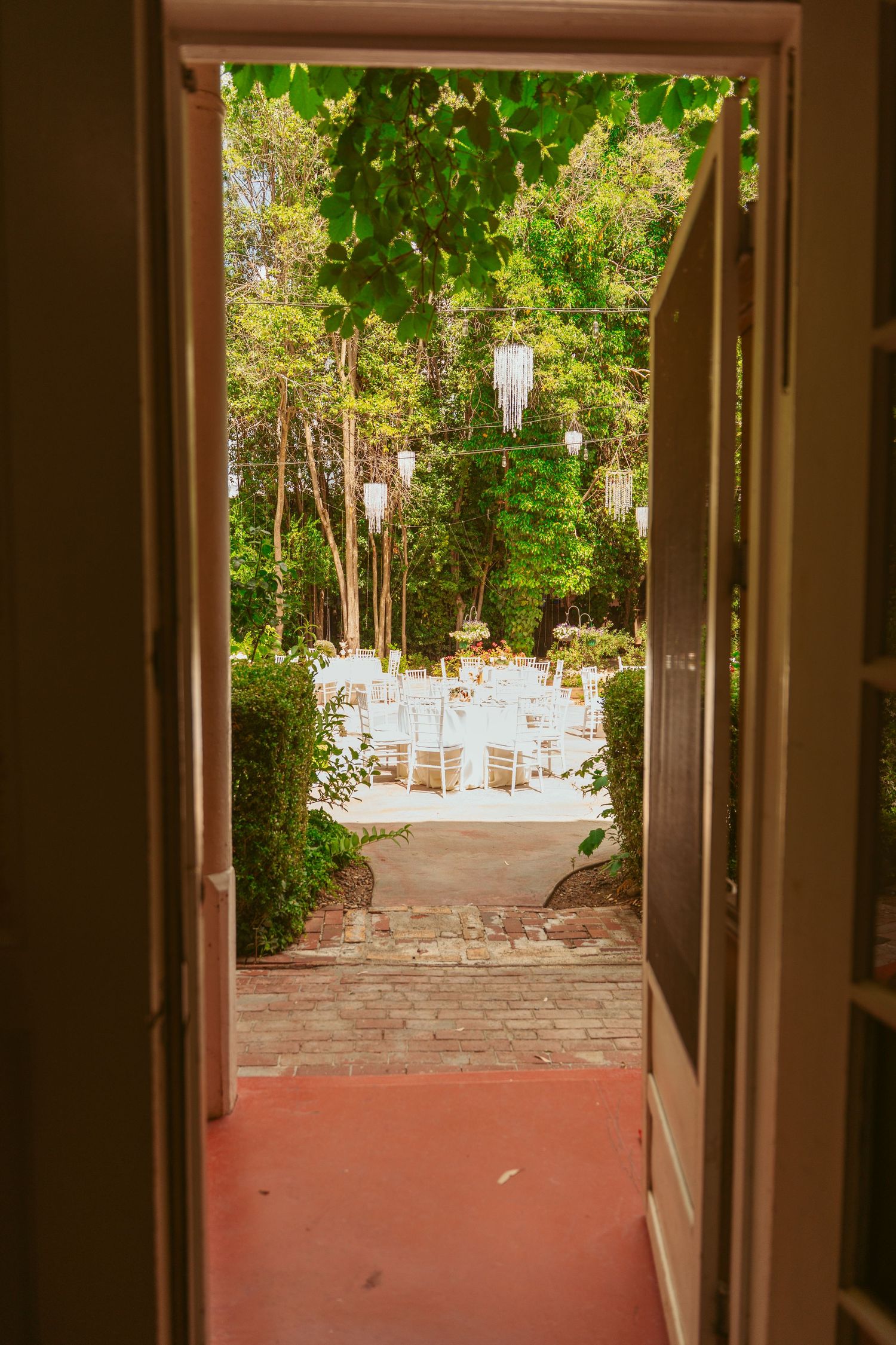 Doorway view of an outdoor wedding venue with stone pathways and garden landscaping.