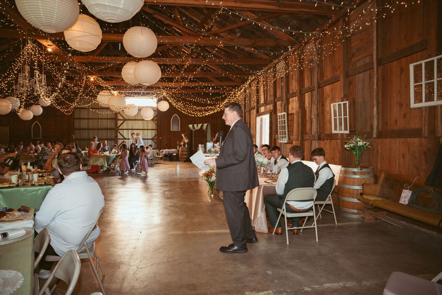 Panoramic view of a barn wedding venue with romantic string light decorations.