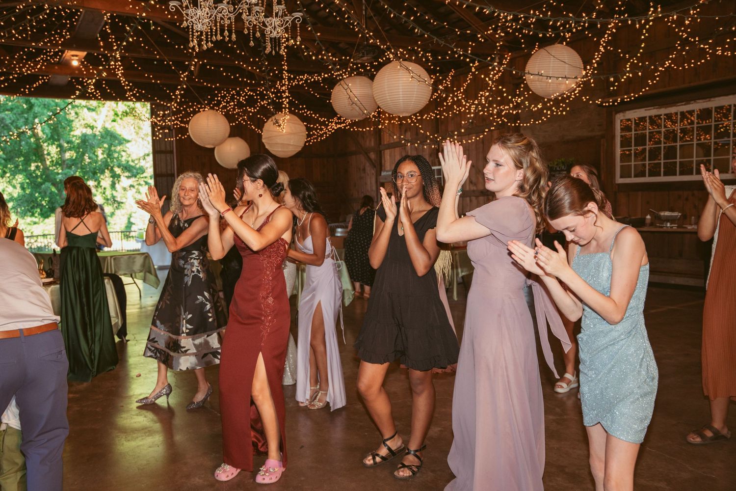 Guests enjoying a lively dance party under decorative string lights at a wedding reception.
