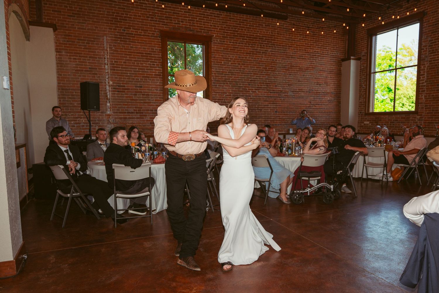Wedding reception venue with exposed brick walls and string lights creating a warm atmosphere.