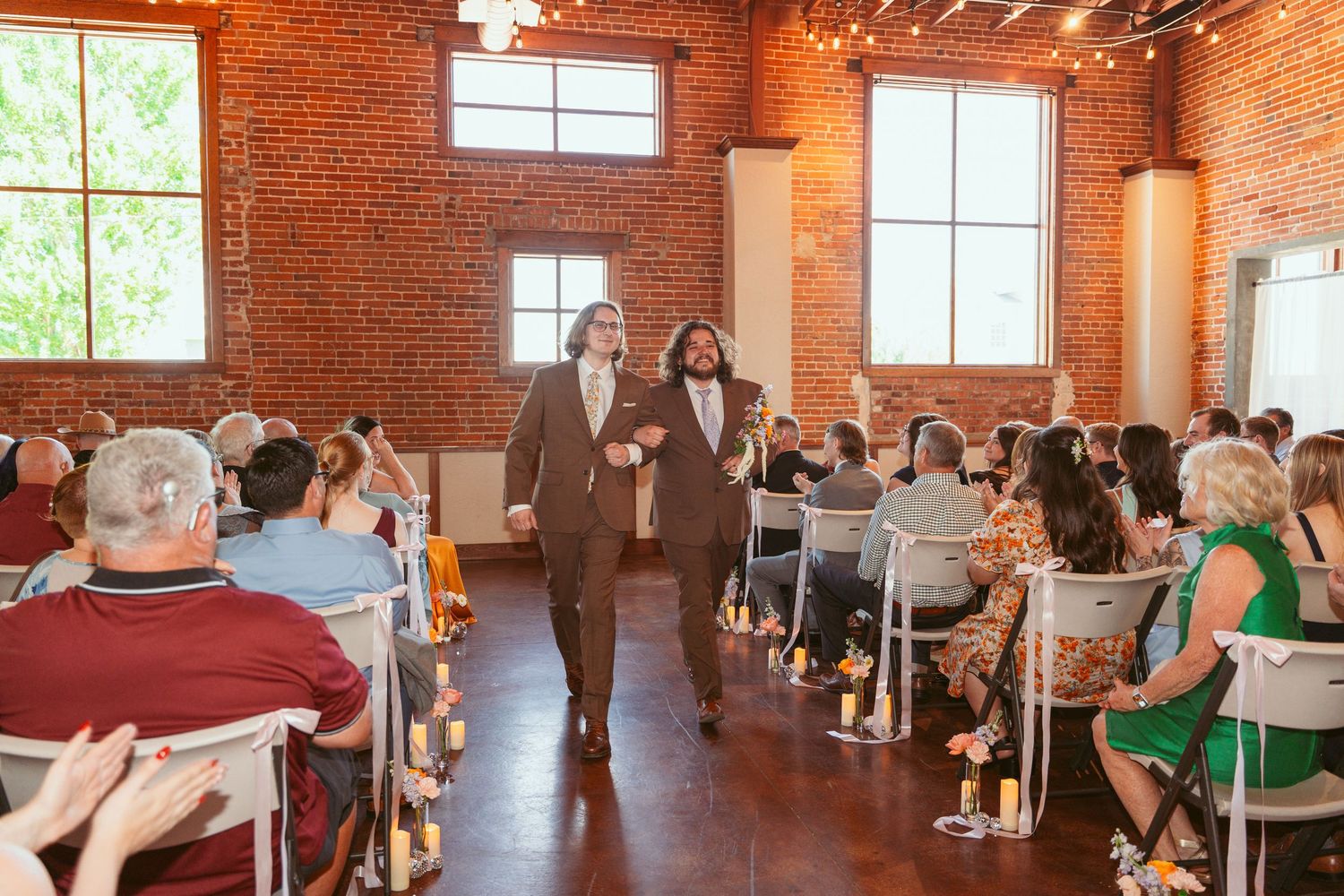 Wedding ceremony space in historic brick building with string lights and natural window lighting.