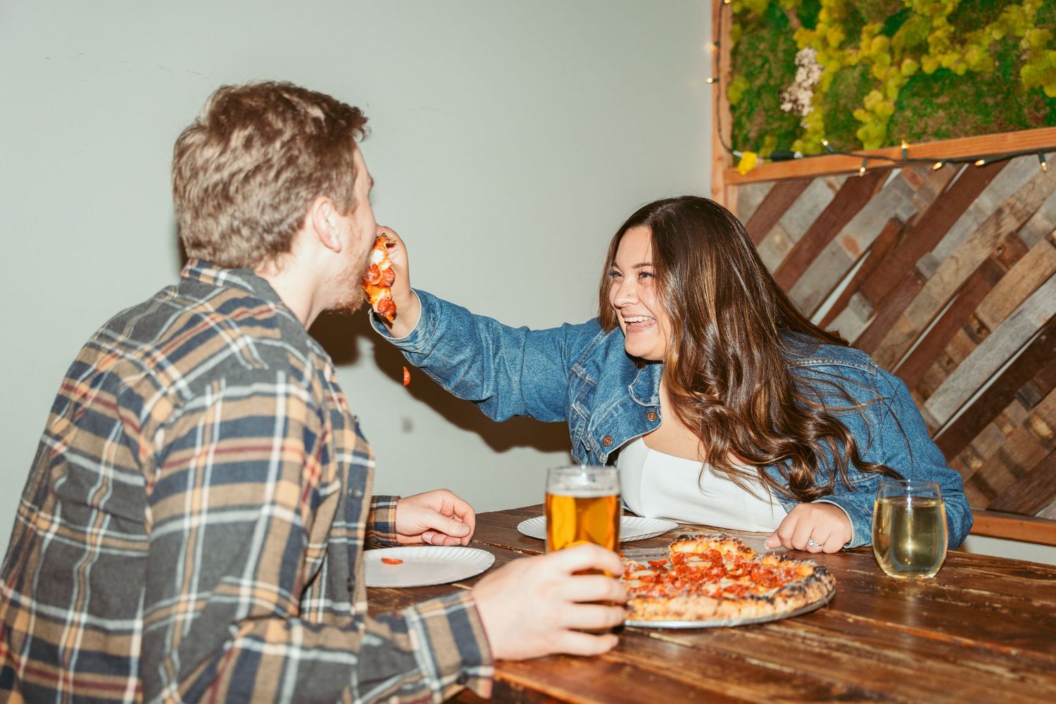 Group sharing a casual meal with pizza and beverages at a rustic table setting.