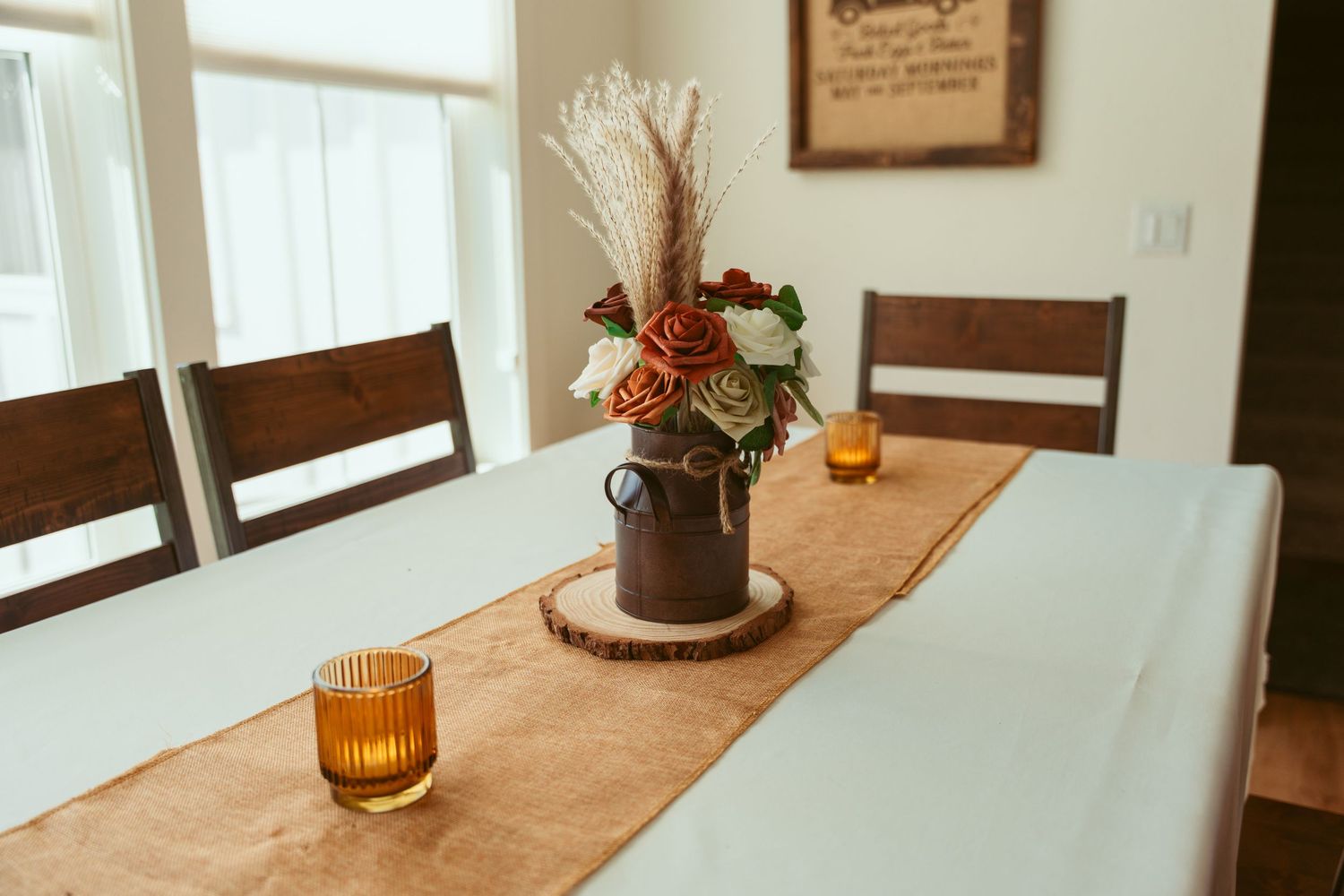 Wedding reception table decorated with burlap runner, candles and rustic wooden elements.