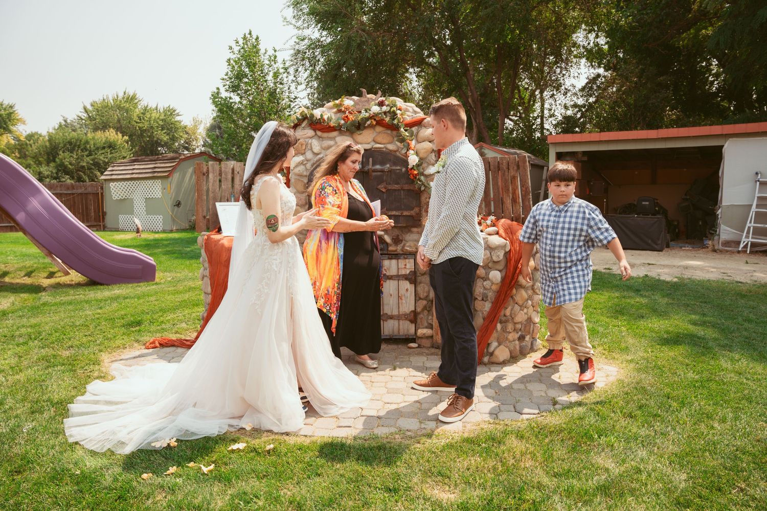 Wedding party posing and playing on grass in an outdoor setting.