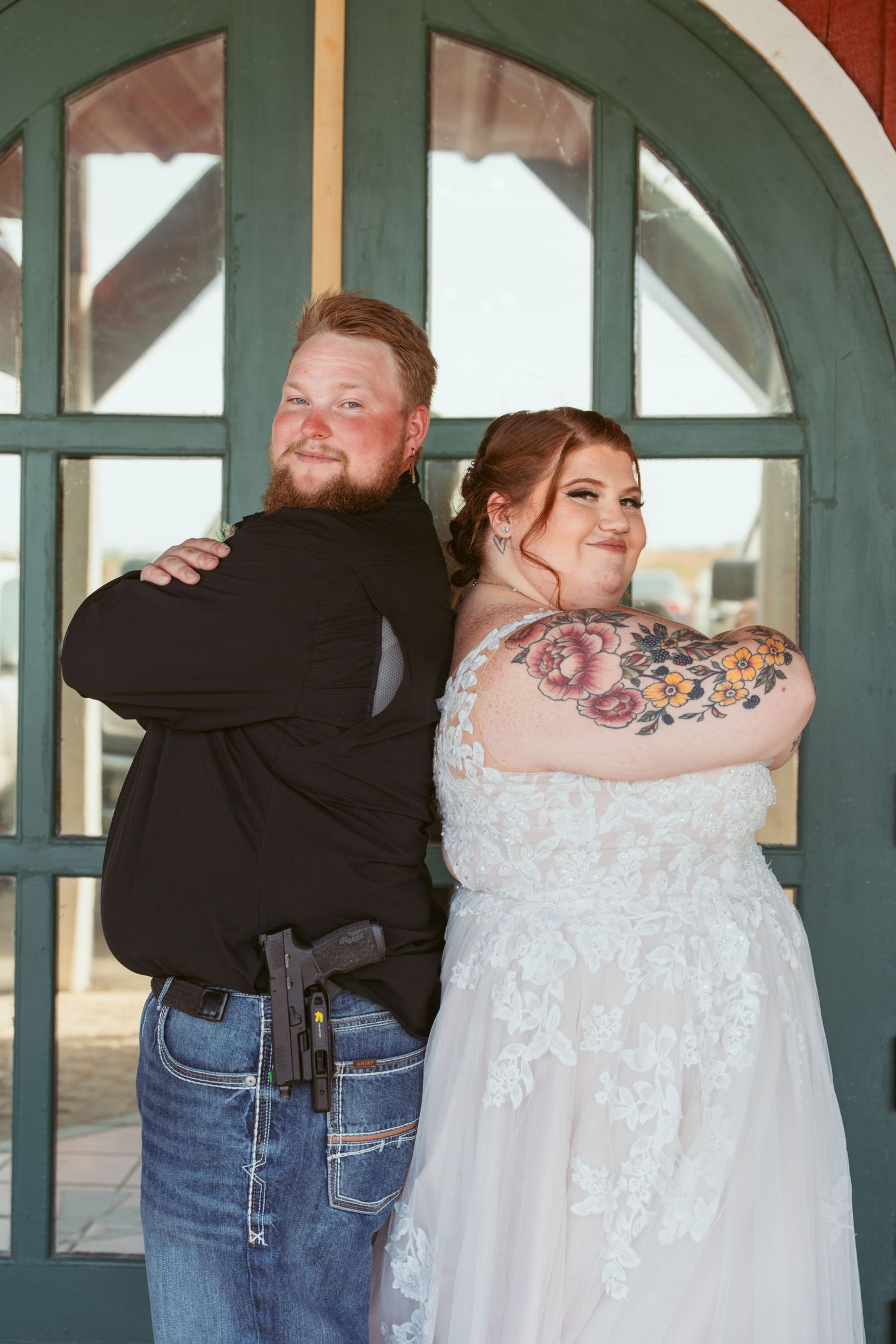 Wedding party members in casual attire embrace and pose playfully under arched windows.