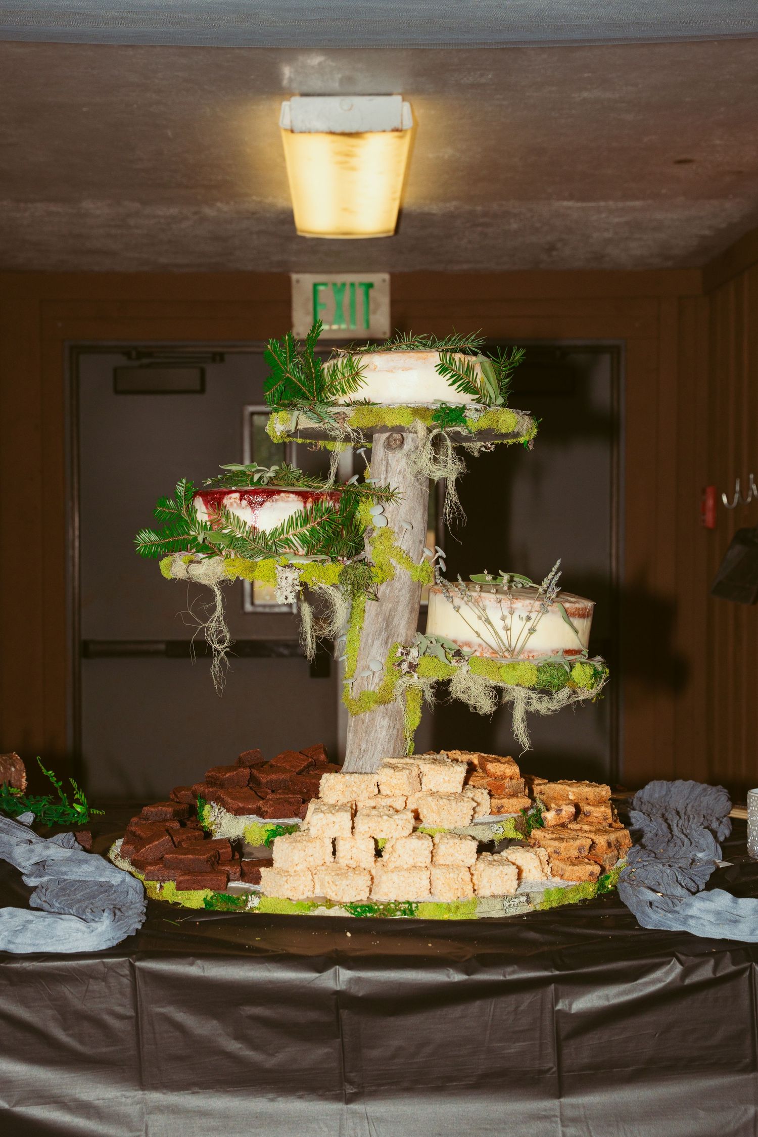 Large catering display with tiered food platters and greenery decorations.