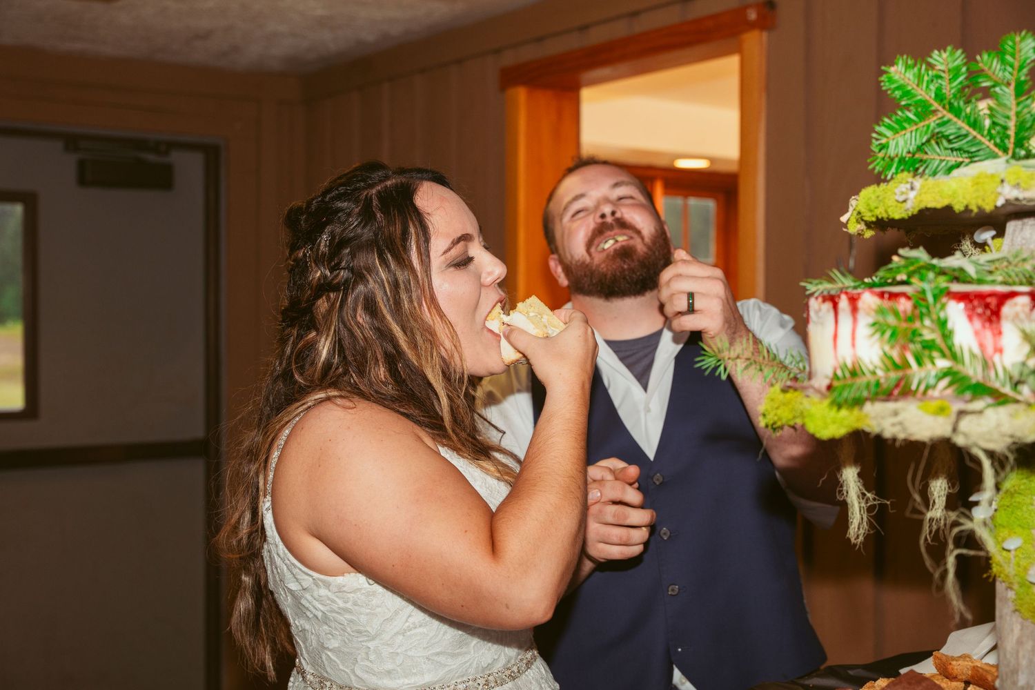 A playful wedding cake cutting moment with a couple sharing dessert at their reception.