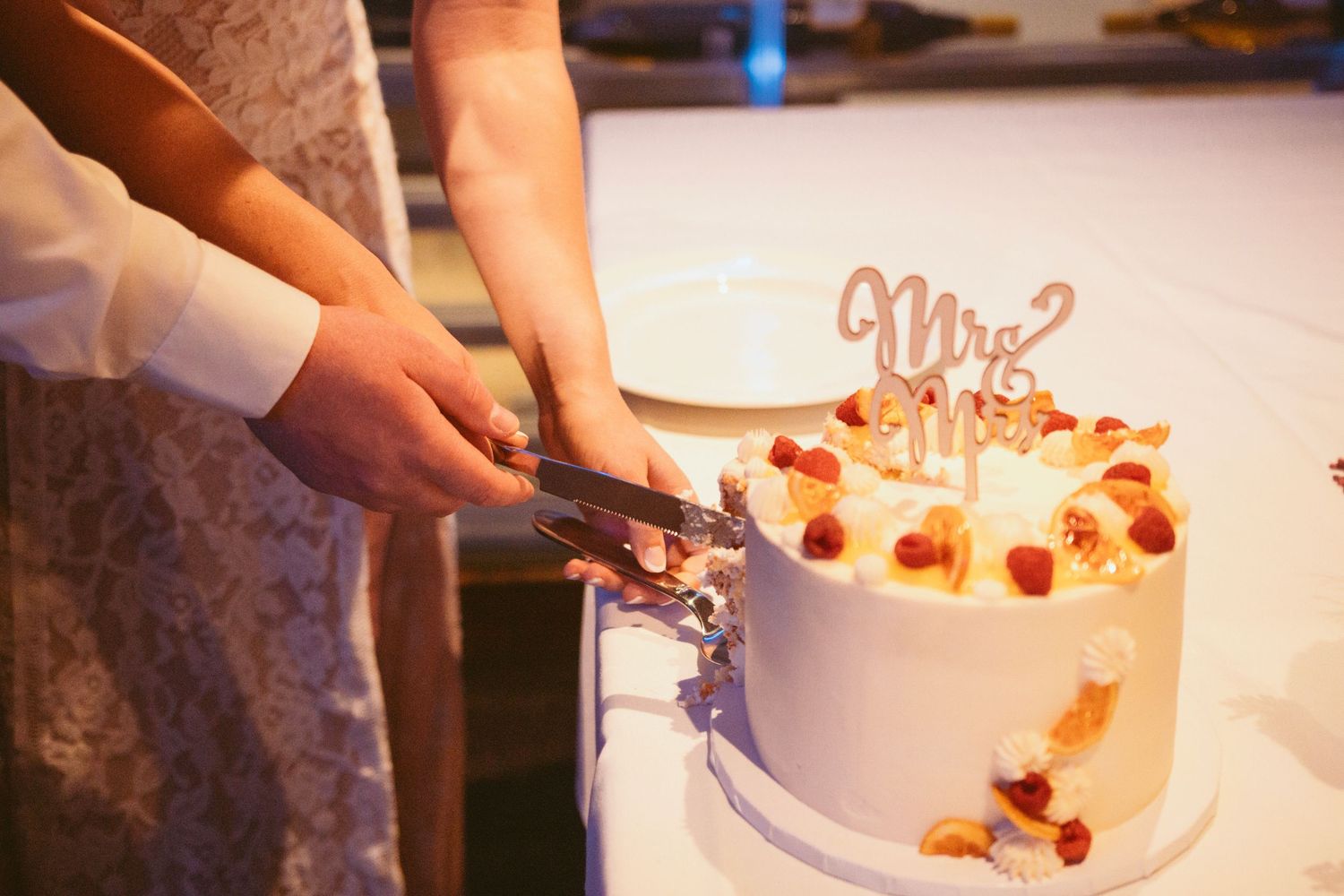 Detail shot of someone placing decorative elements on a pristine white wedding cake.