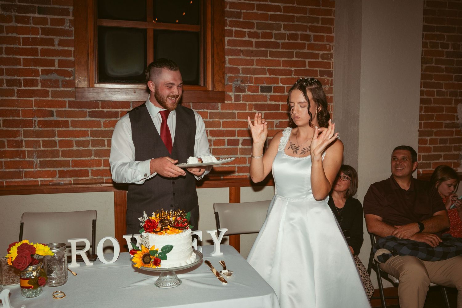Wedding reception activities with cake and dancing against exposed brick walls.