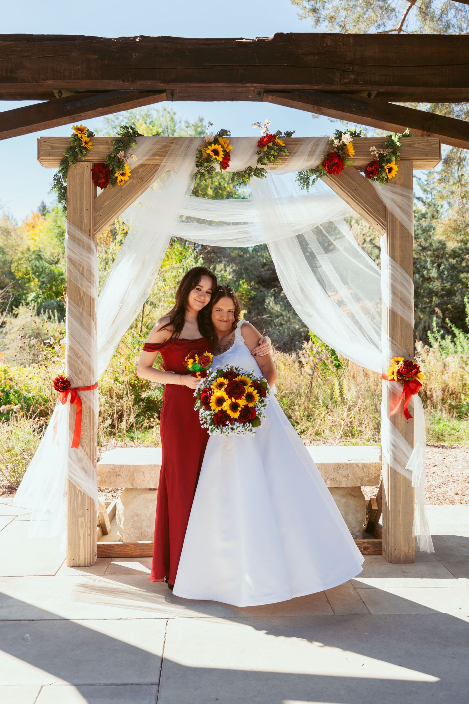 Wedding celebration under a rustic pavilion decorated with white drapes and sunflower bouquets.