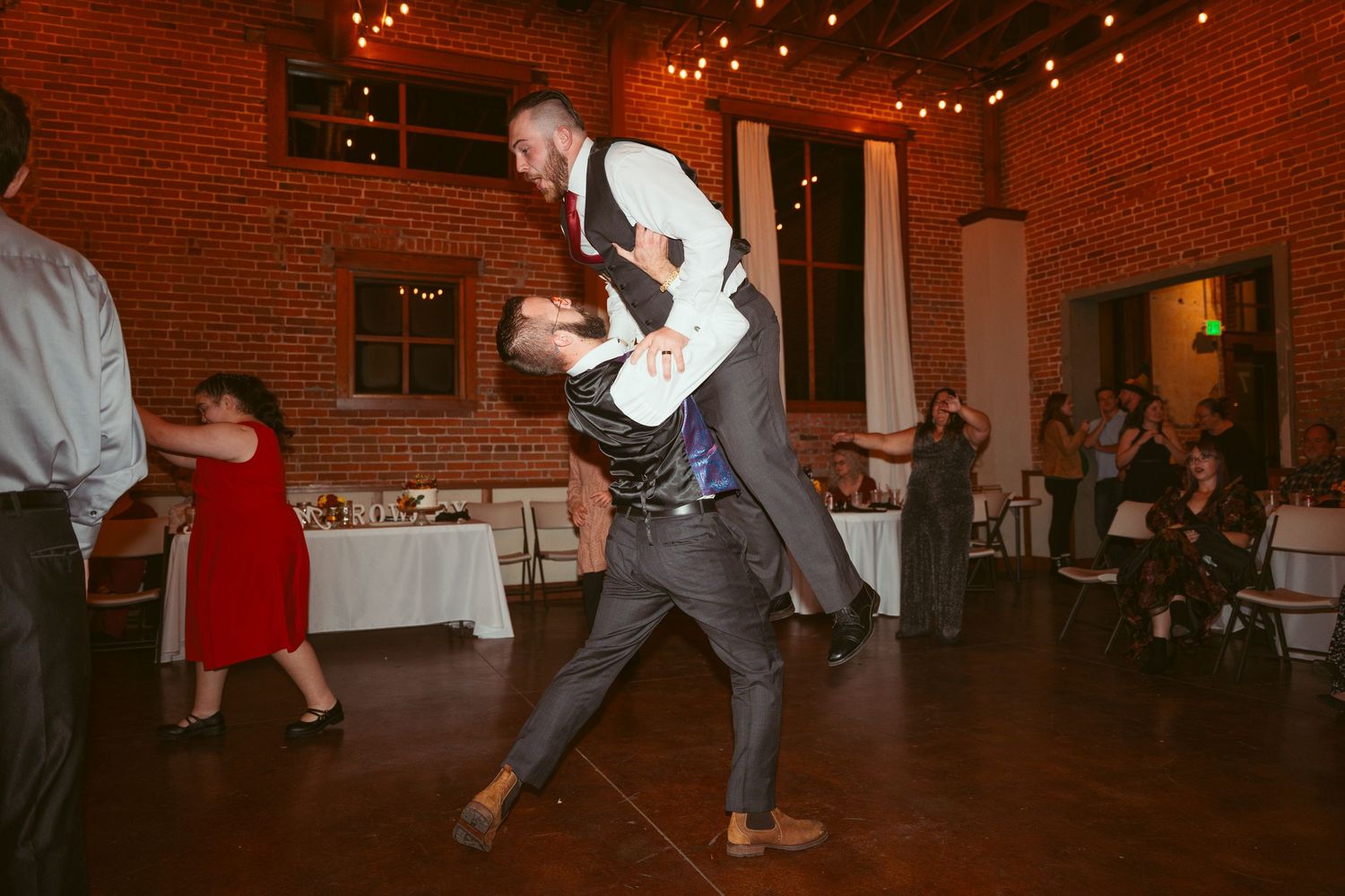 Couple performing dramatic dance moves at wedding reception with guests watching.