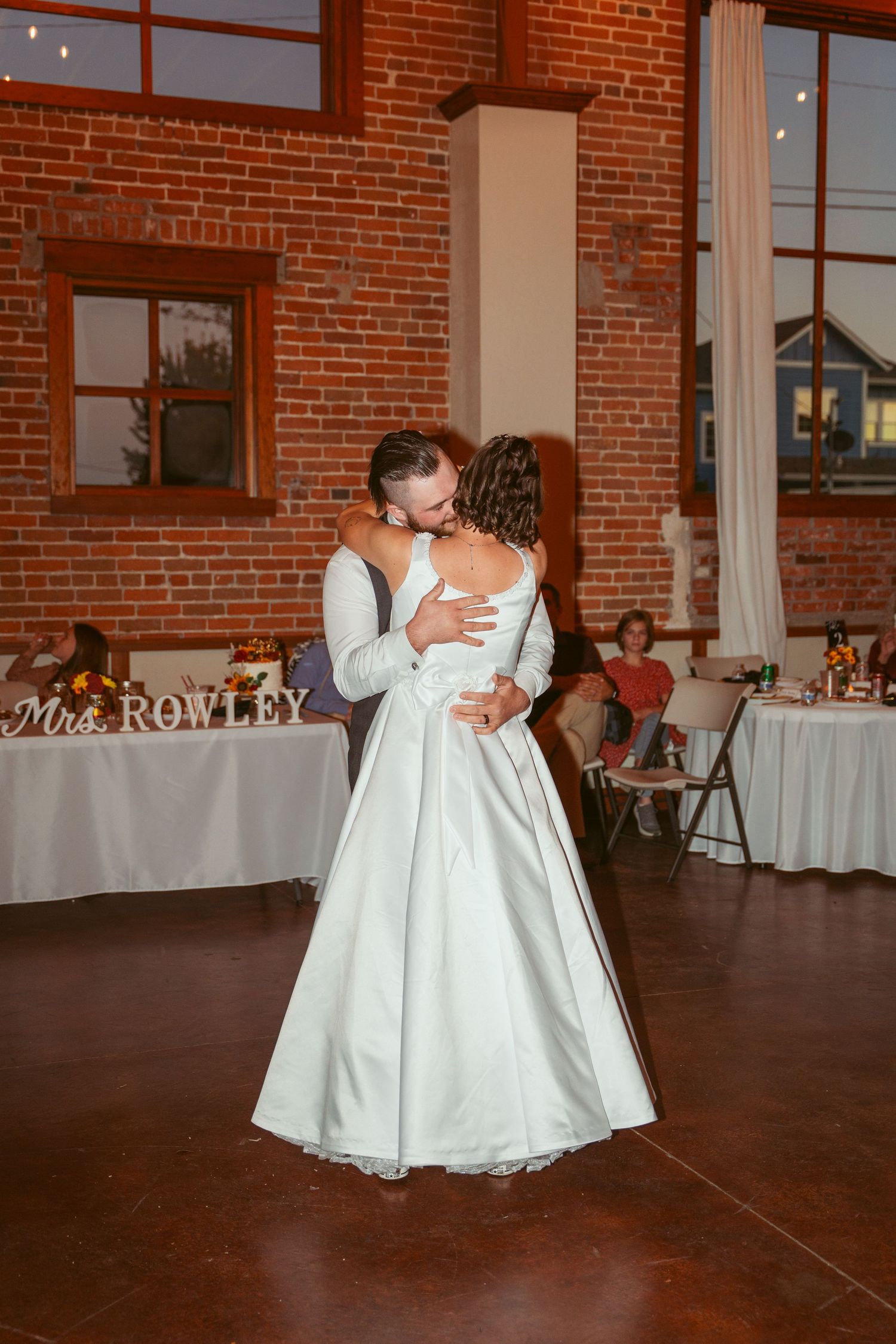 A wedding dance sequence captured in a rustic brick venue with elegant white table settings.