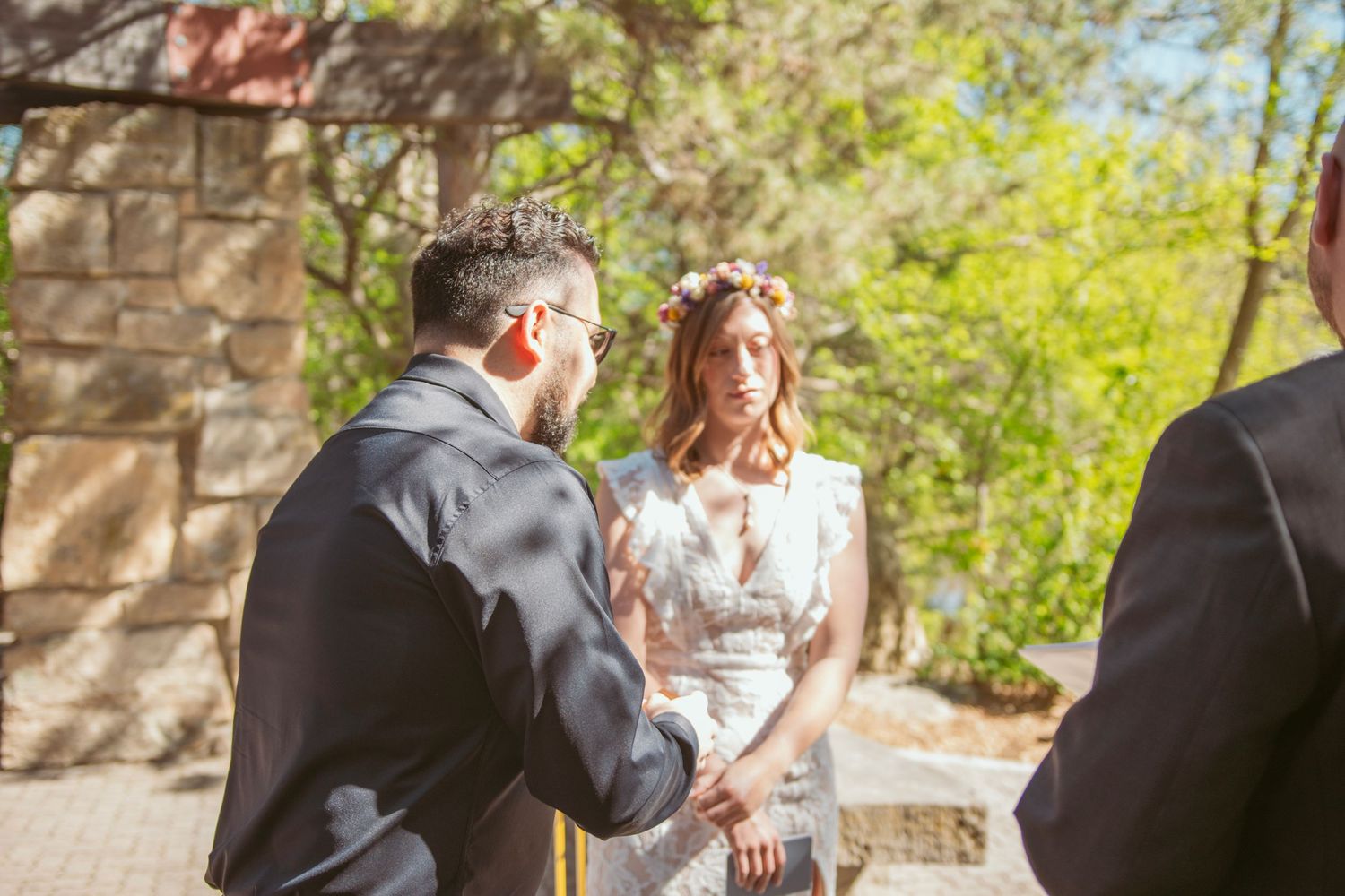A couple shares an intimate moment during their wedding ceremony on a sunny day.