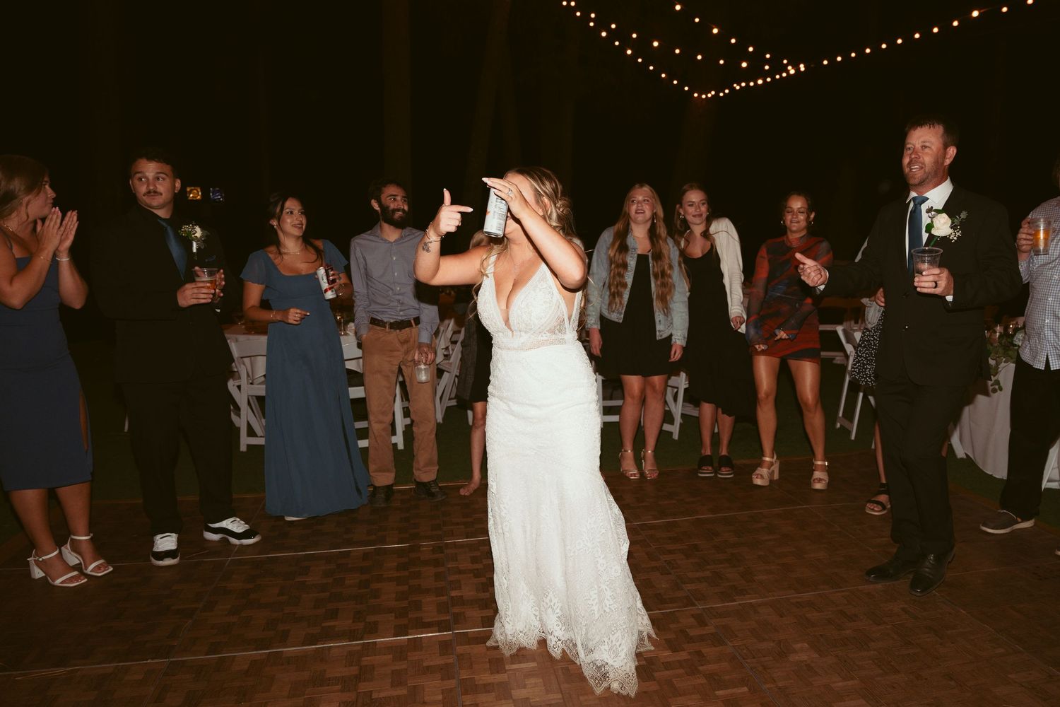 Guests dancing and celebrating at a nighttime wedding reception on an outdoor patio.