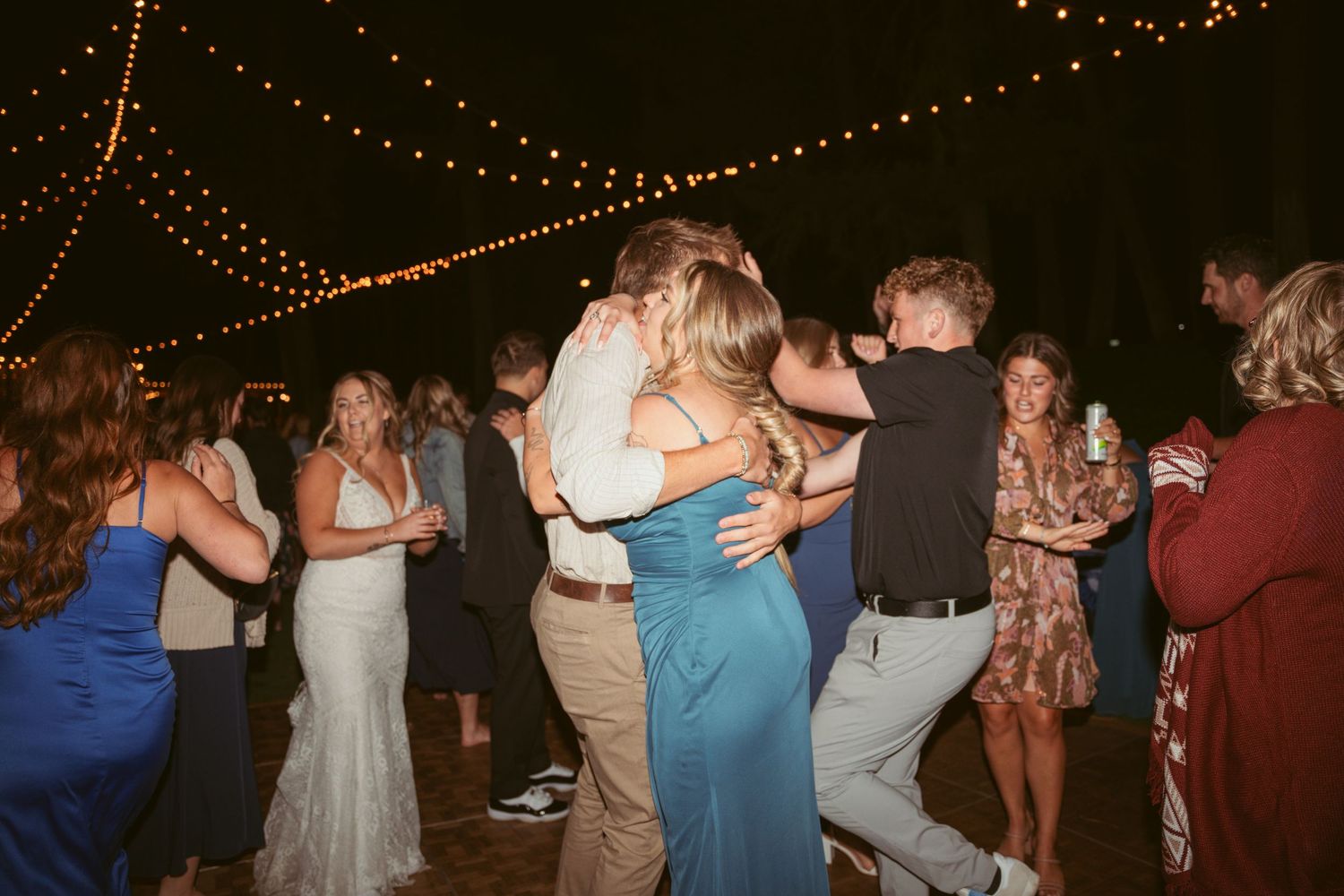 Couples embracing while dancing at a festive outdoor evening celebration.
